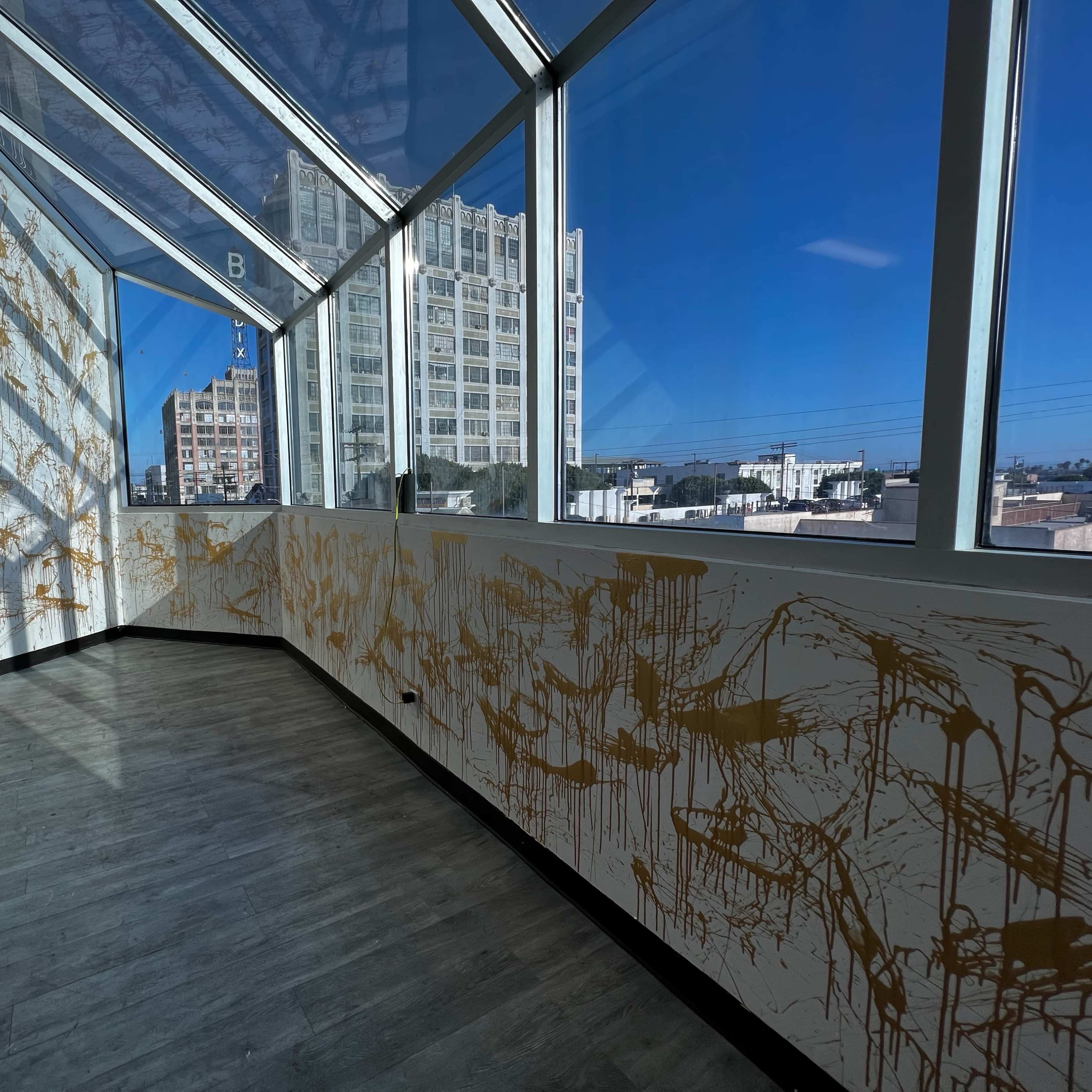 An empty room with large windows and walls decorated with gold splatter paint.