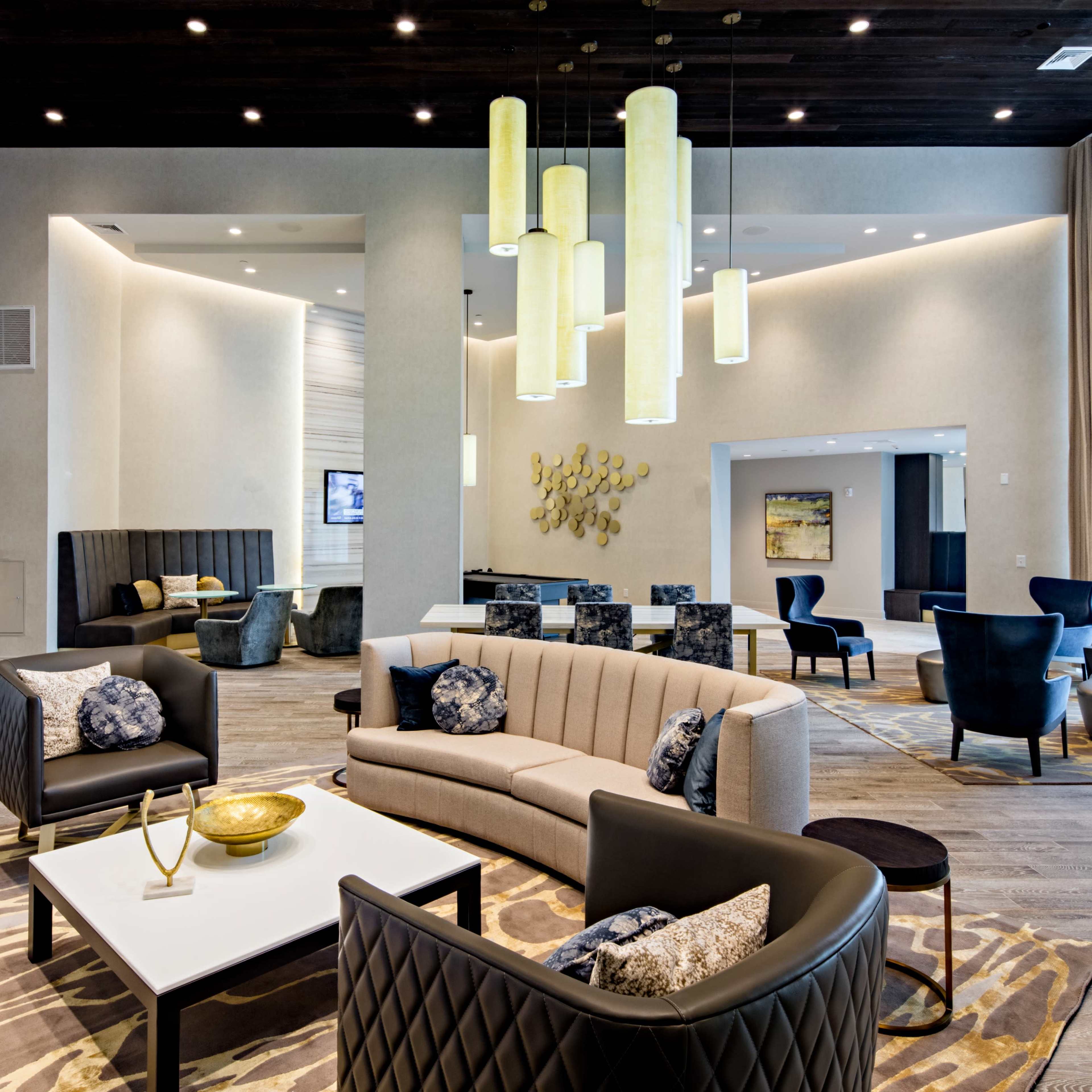 A modern lounge area with stylish seating, a large light fixture, and contemporary decor.