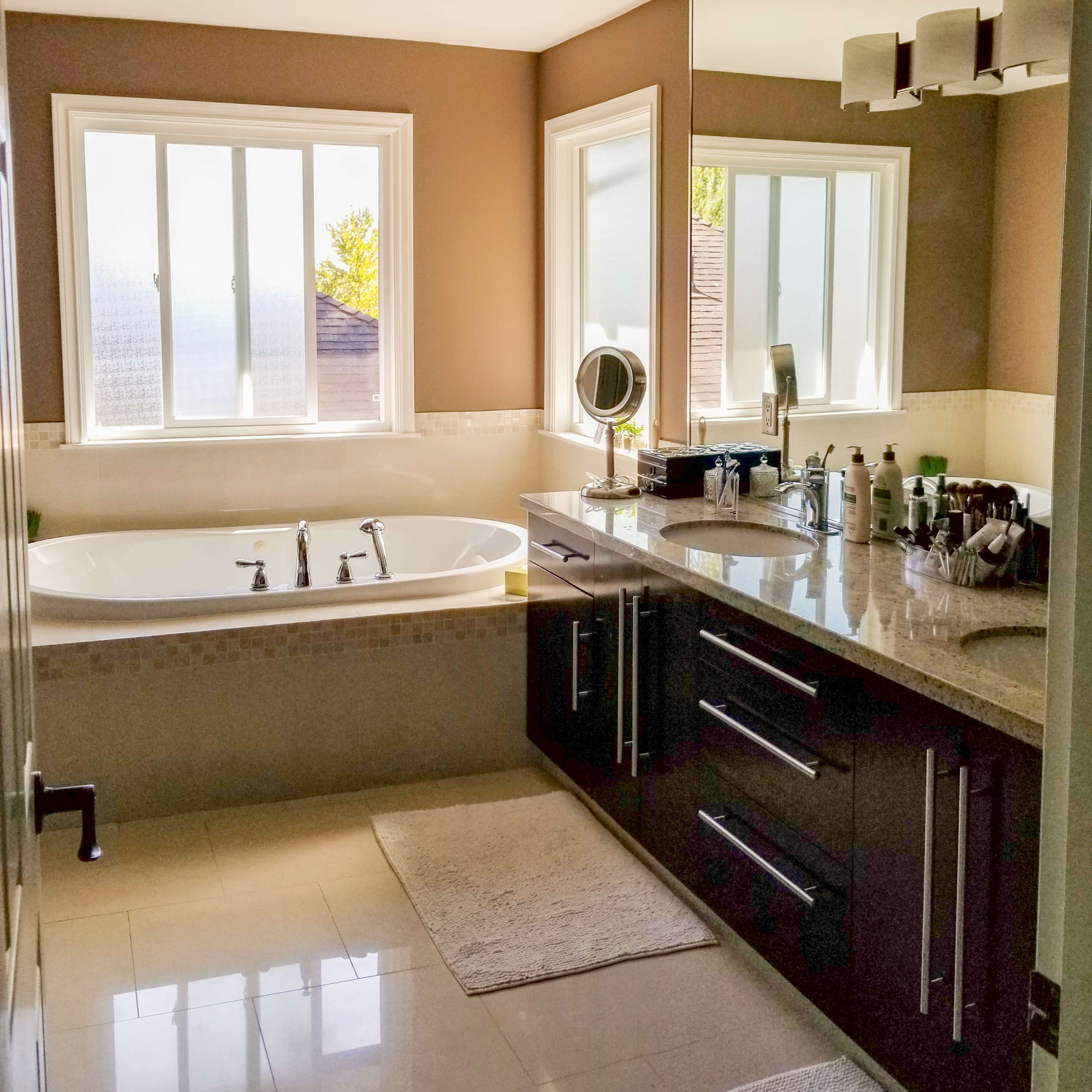 A modern bathroom featuring a large bathtub, a double vanity with a sink, and a large mirror above the countertop.