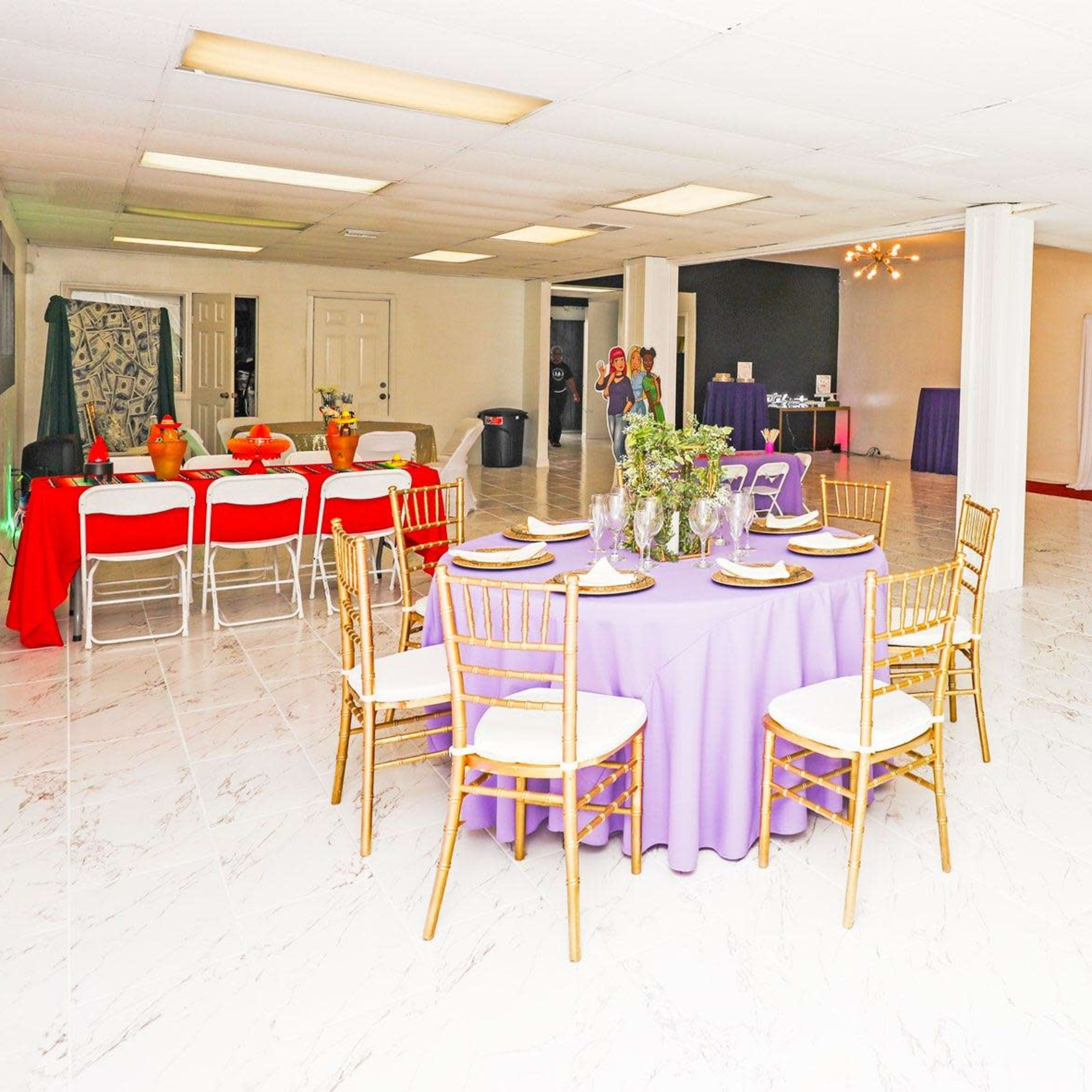 A spacious event room set up with several tables, including a purple round table, and a buffet area along one wall.