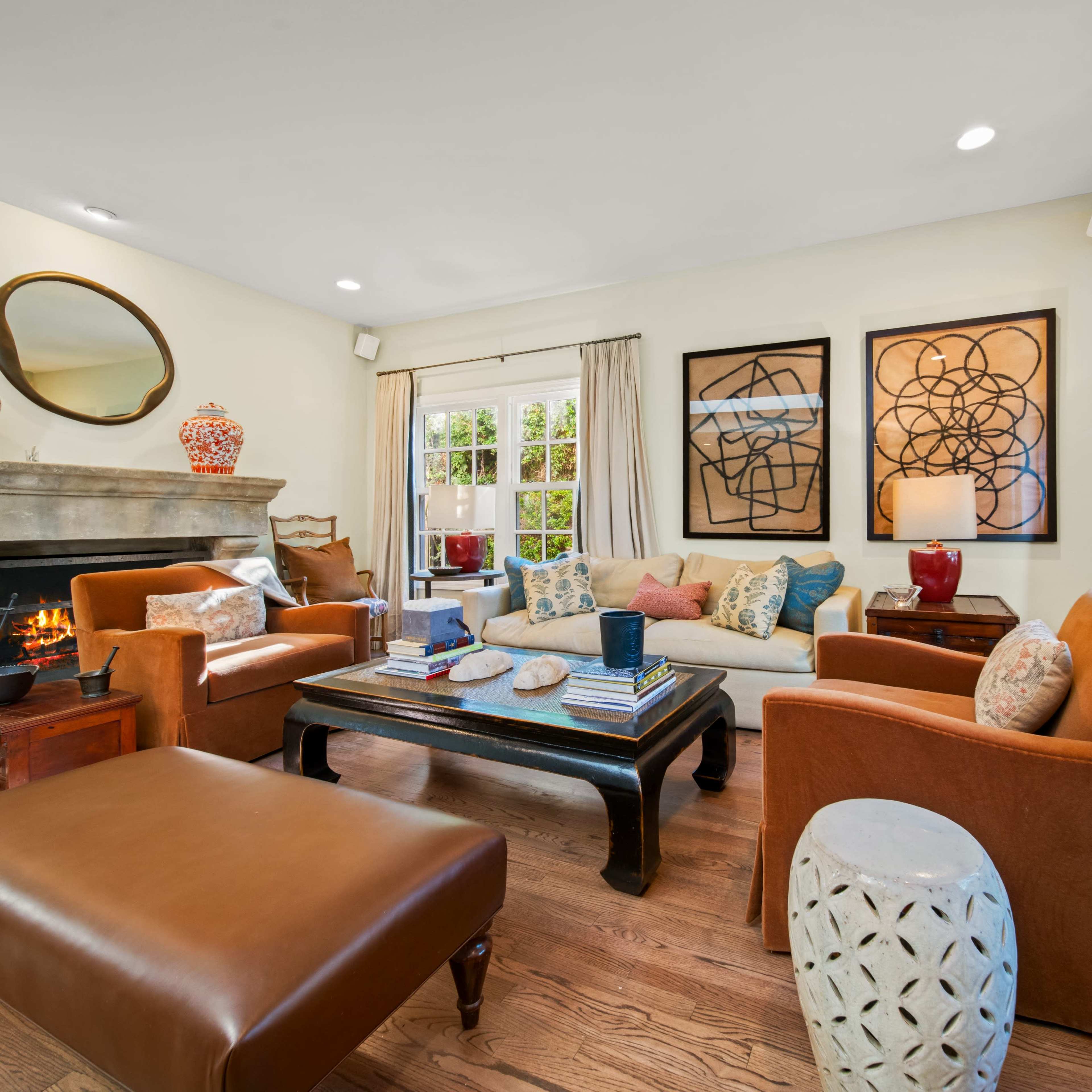 The living room features a central seating area with a sofa and chairs arranged around a coffee table, complemented by decorative art and a fireplace.
