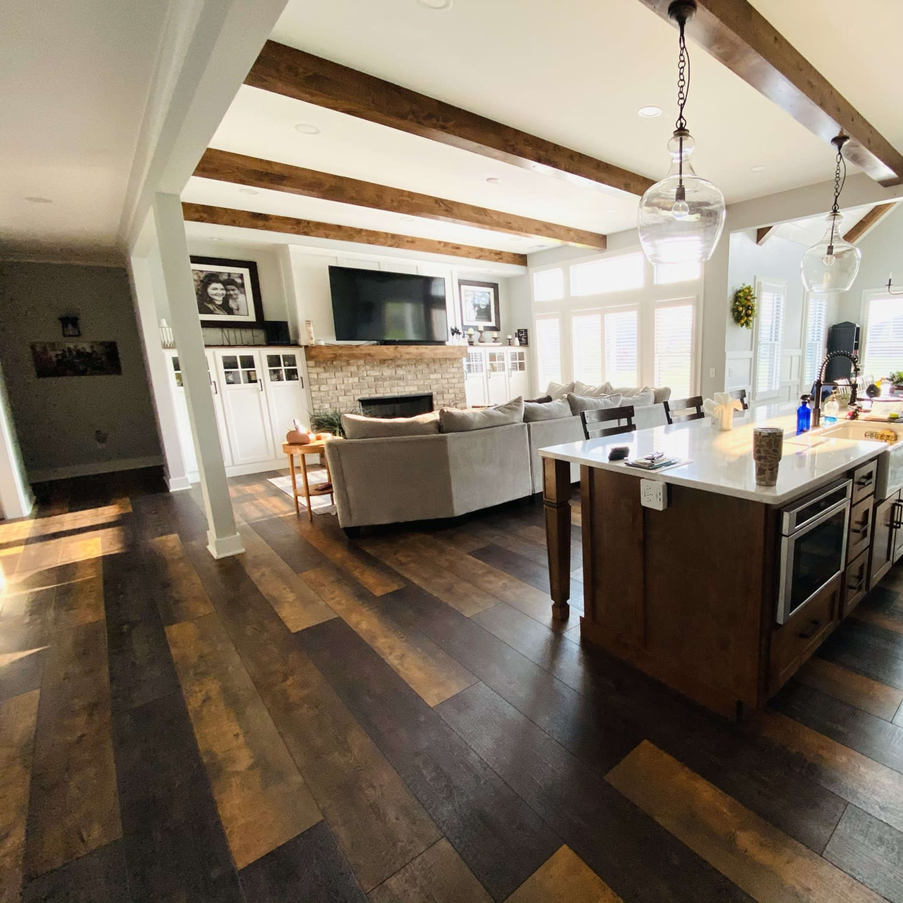 A spacious living area features a modern kitchen island, a seating area with a sectional sofa, and large windows allowing natural light to fill the room.