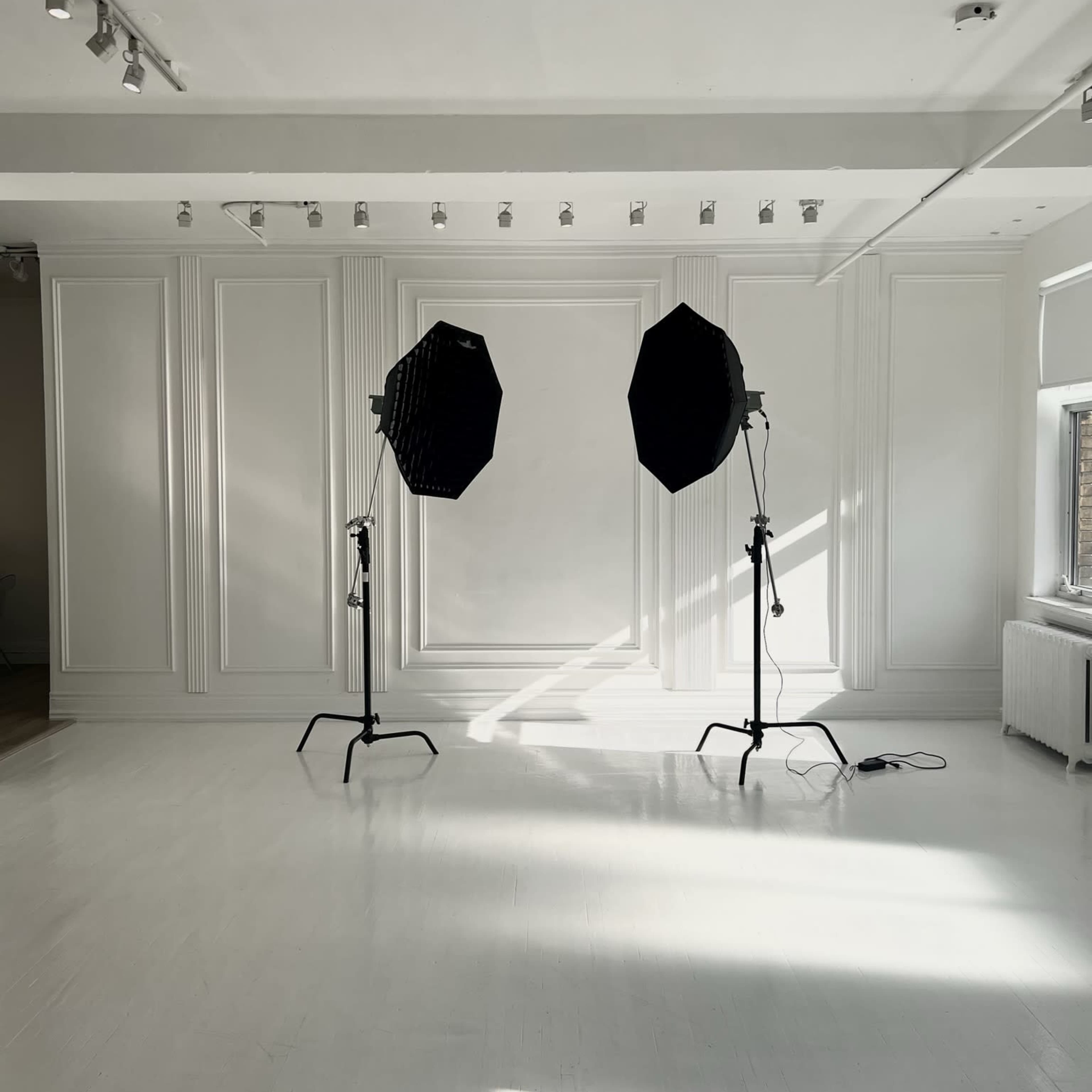 A bright, empty studio space with two large softbox lights positioned on stands.