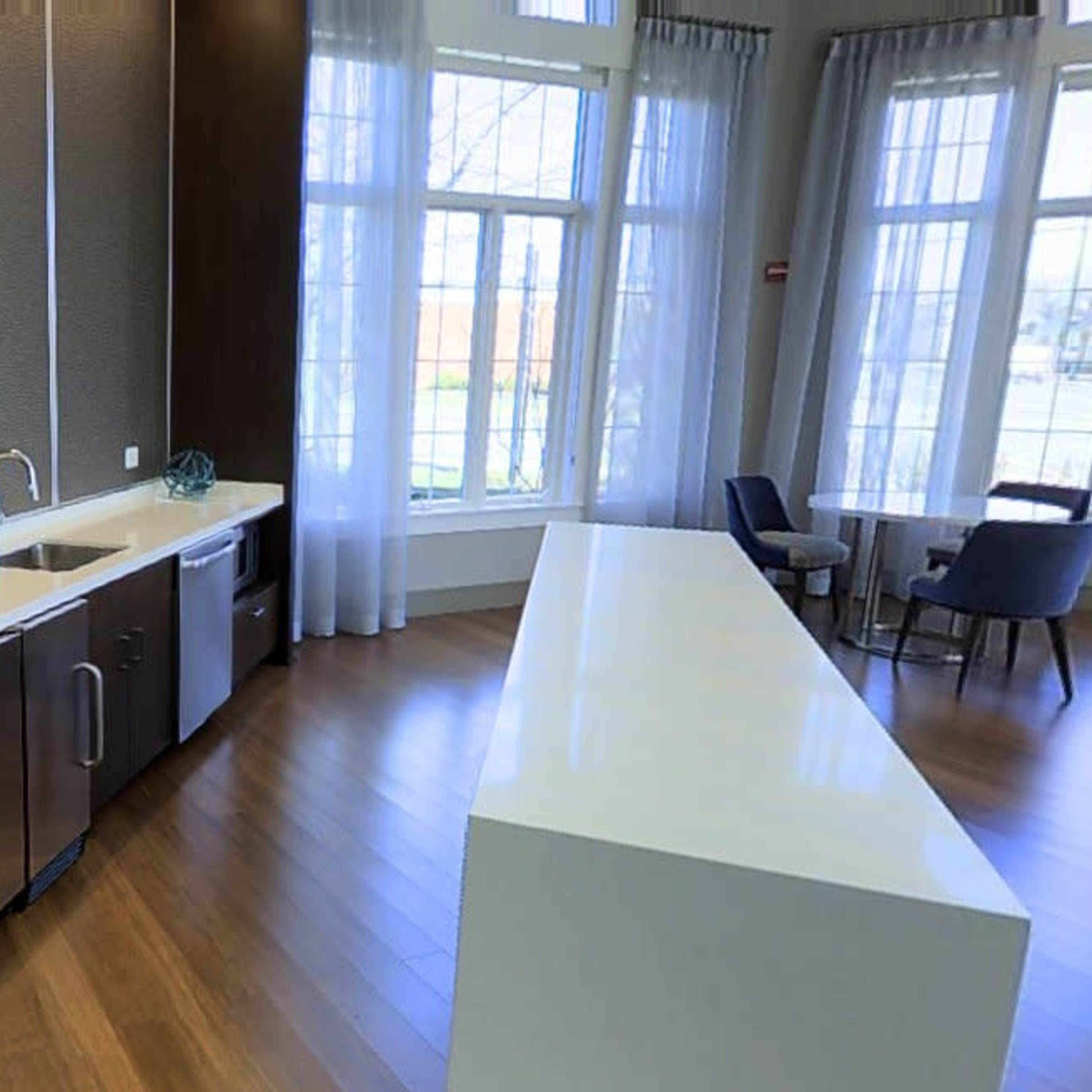 A modern kitchen with a large countertop, stainless steel appliances, and large windows allowing natural light.