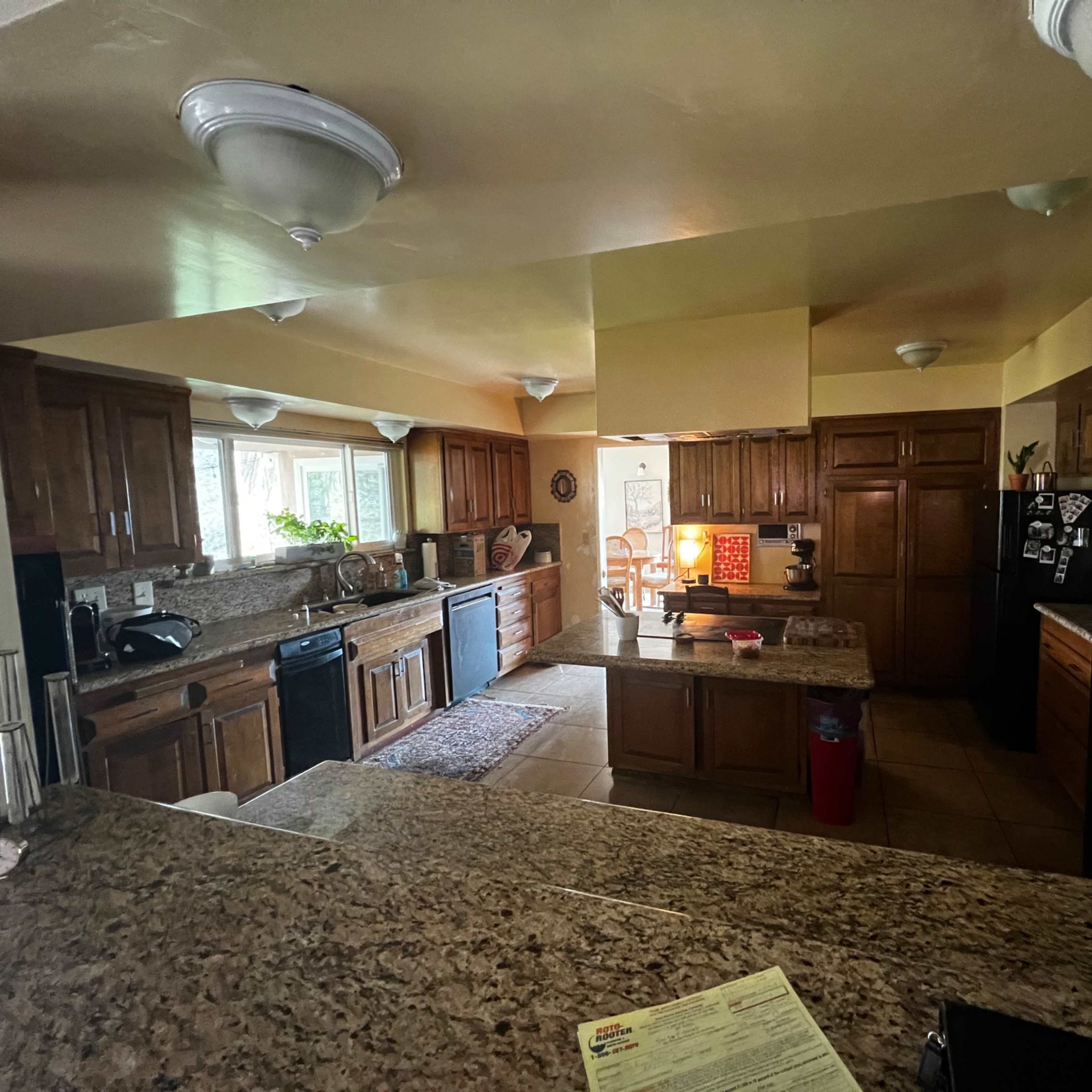 A spacious kitchen with wooden cabinets, granite countertops, and modern appliances, all well-lit by overhead fixtures.