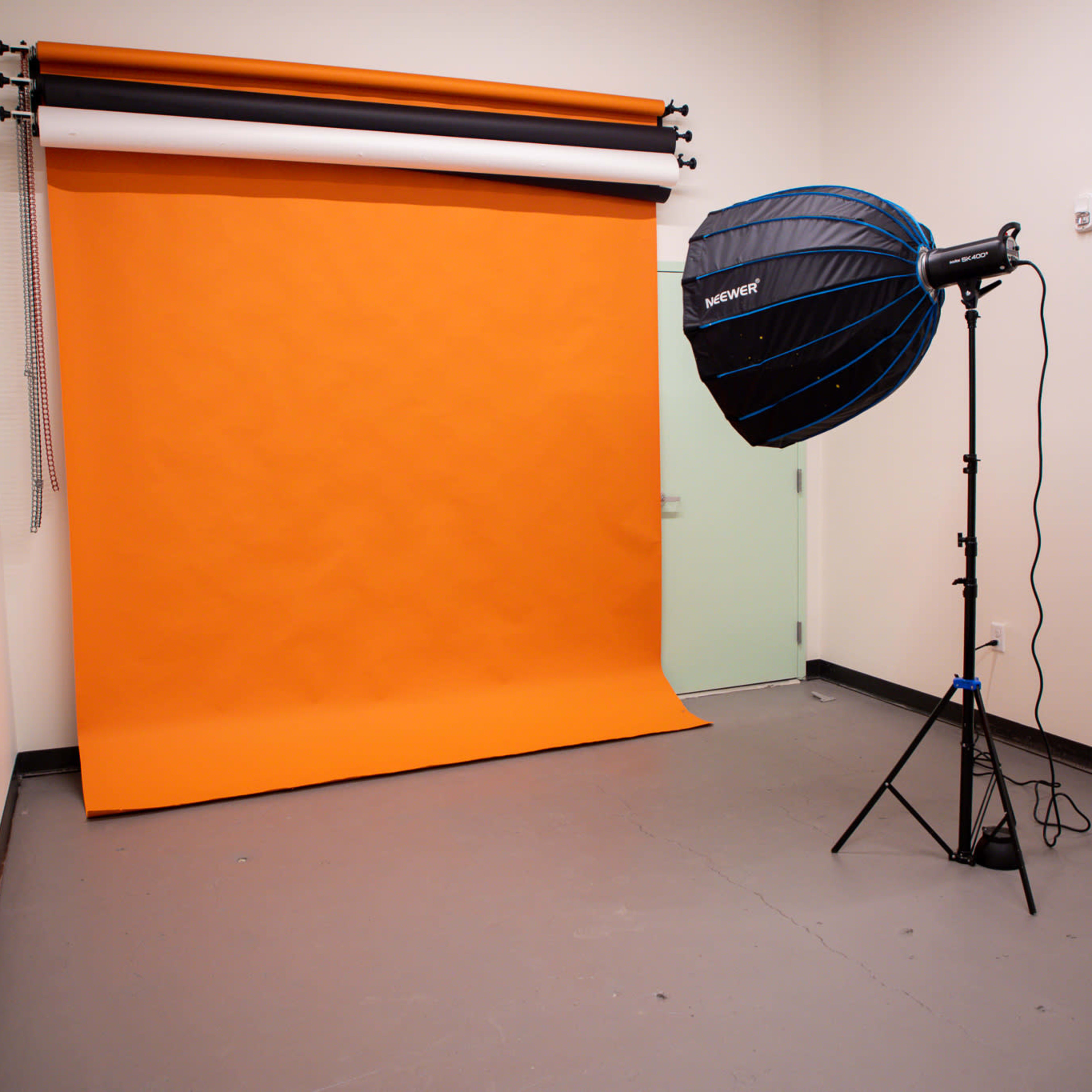 A studio setup with an orange backdrop and a large softbox light on a stand.