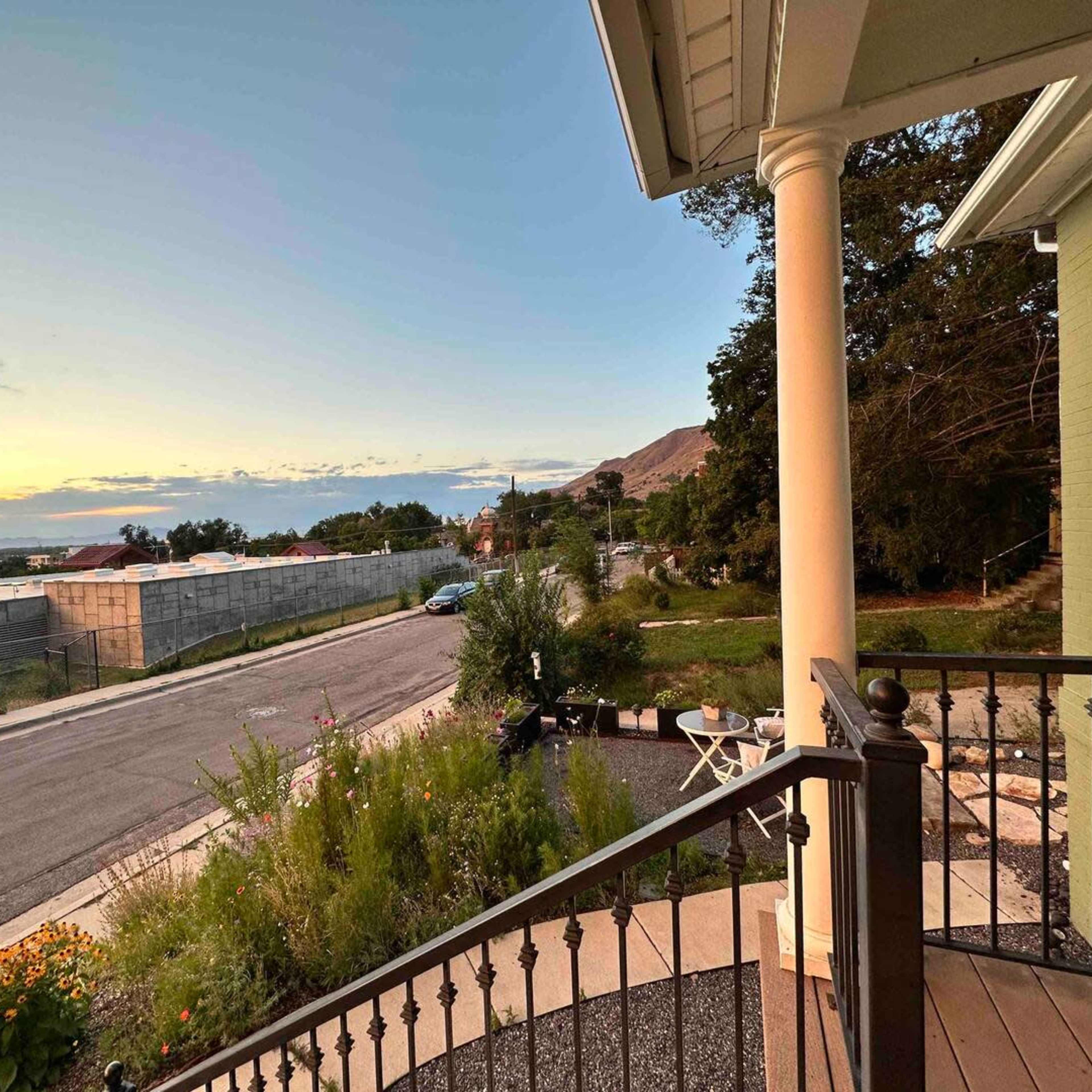 A porch view overlooking a suburban street at sunset, with a mix of residential and natural elements.