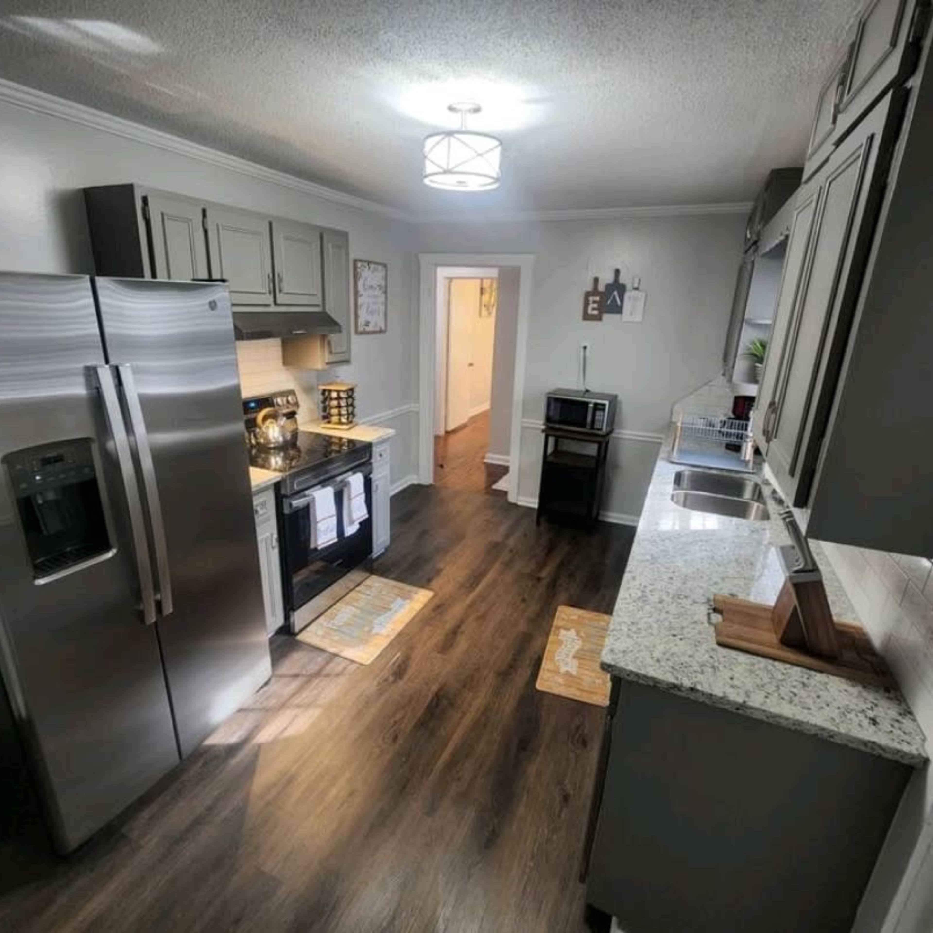 A modern kitchen with stainless steel appliances, gray cabinetry, and a granite countertop.