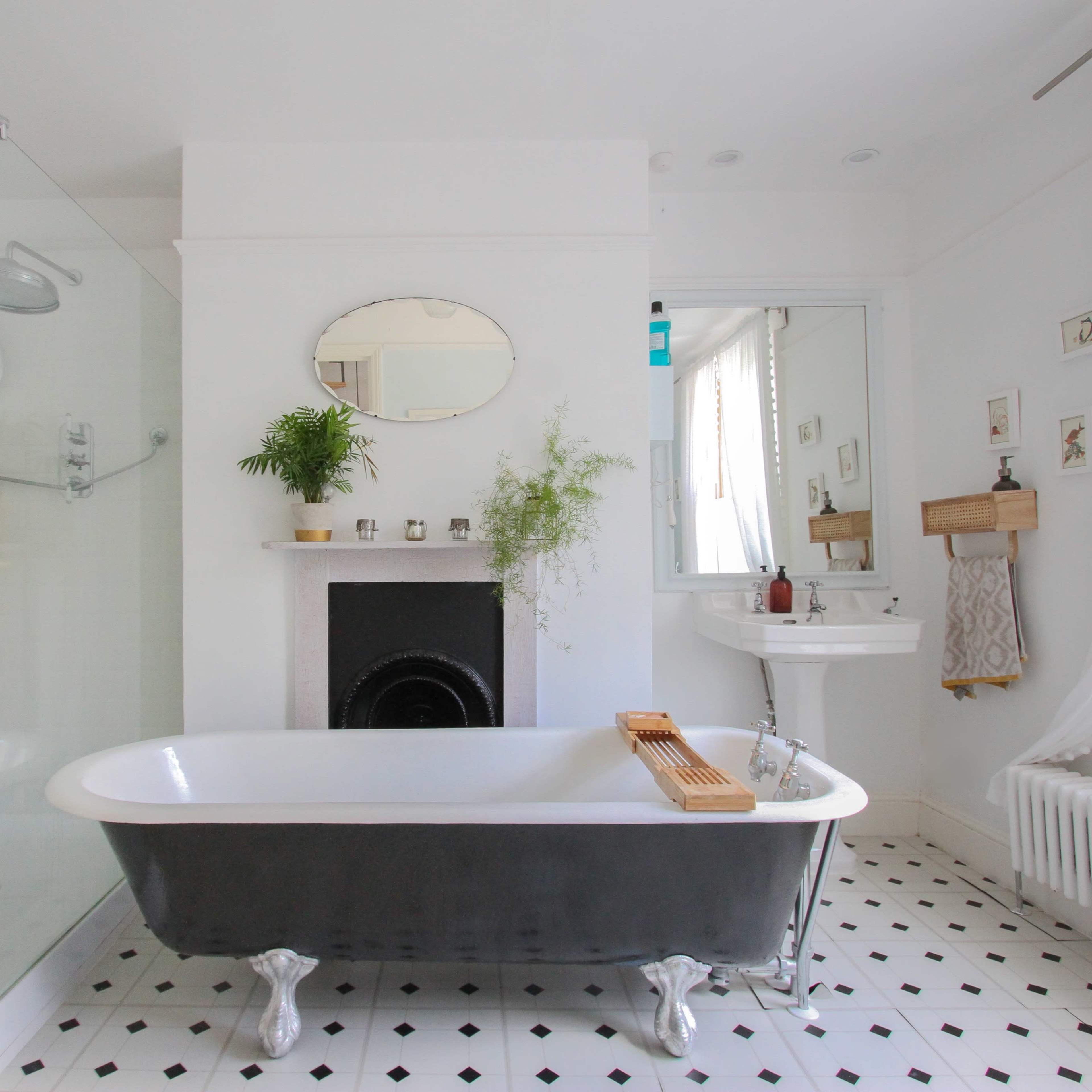 The bathroom features a freestanding clawfoot bathtub, a glass shower enclosure, and a vintage-style sink, all surrounded by white walls and black-and-white tiled flooring.