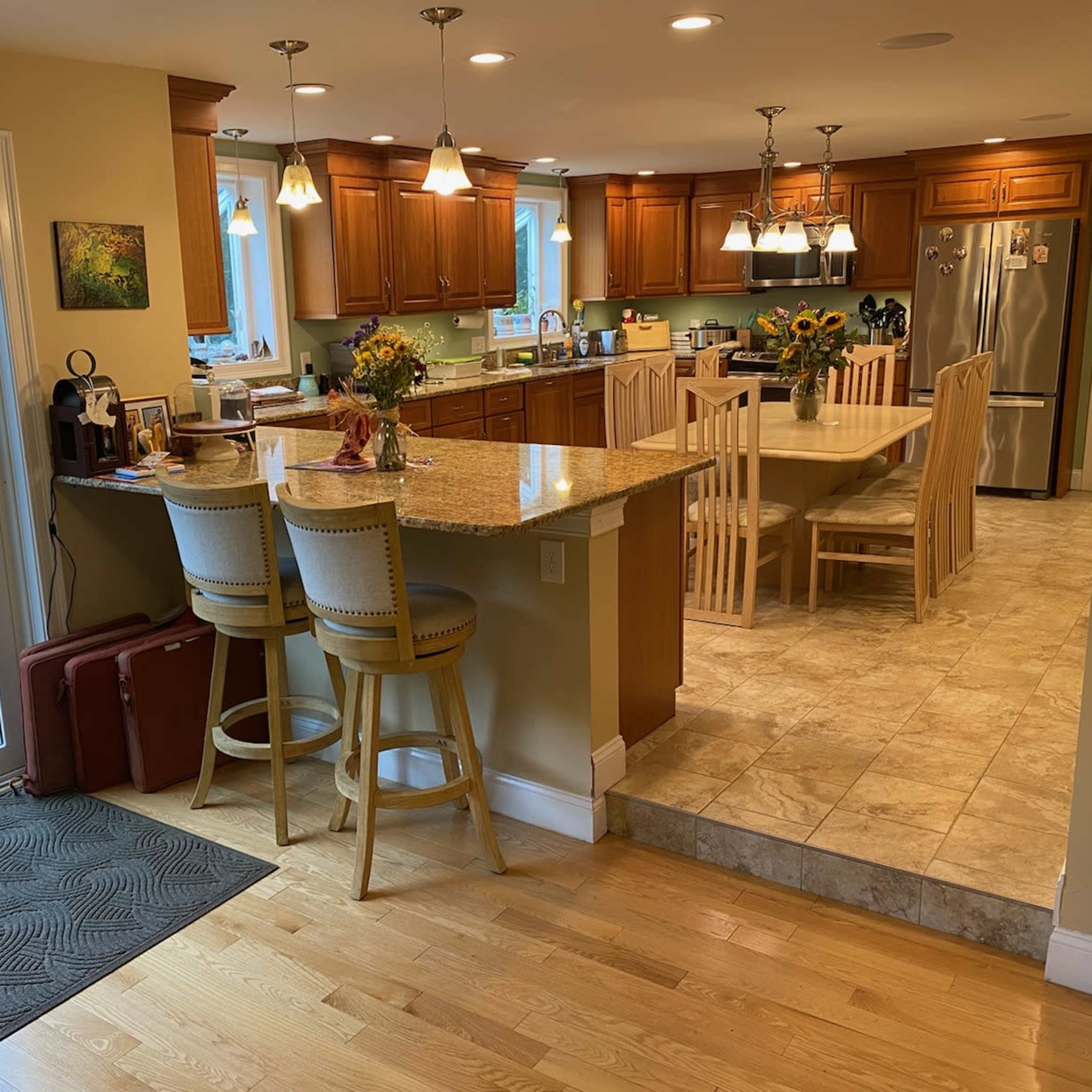 A kitchen features wooden cabinetry, a central island with bar stools, and a view of an outdoor pool area through large sliding glass doors.
