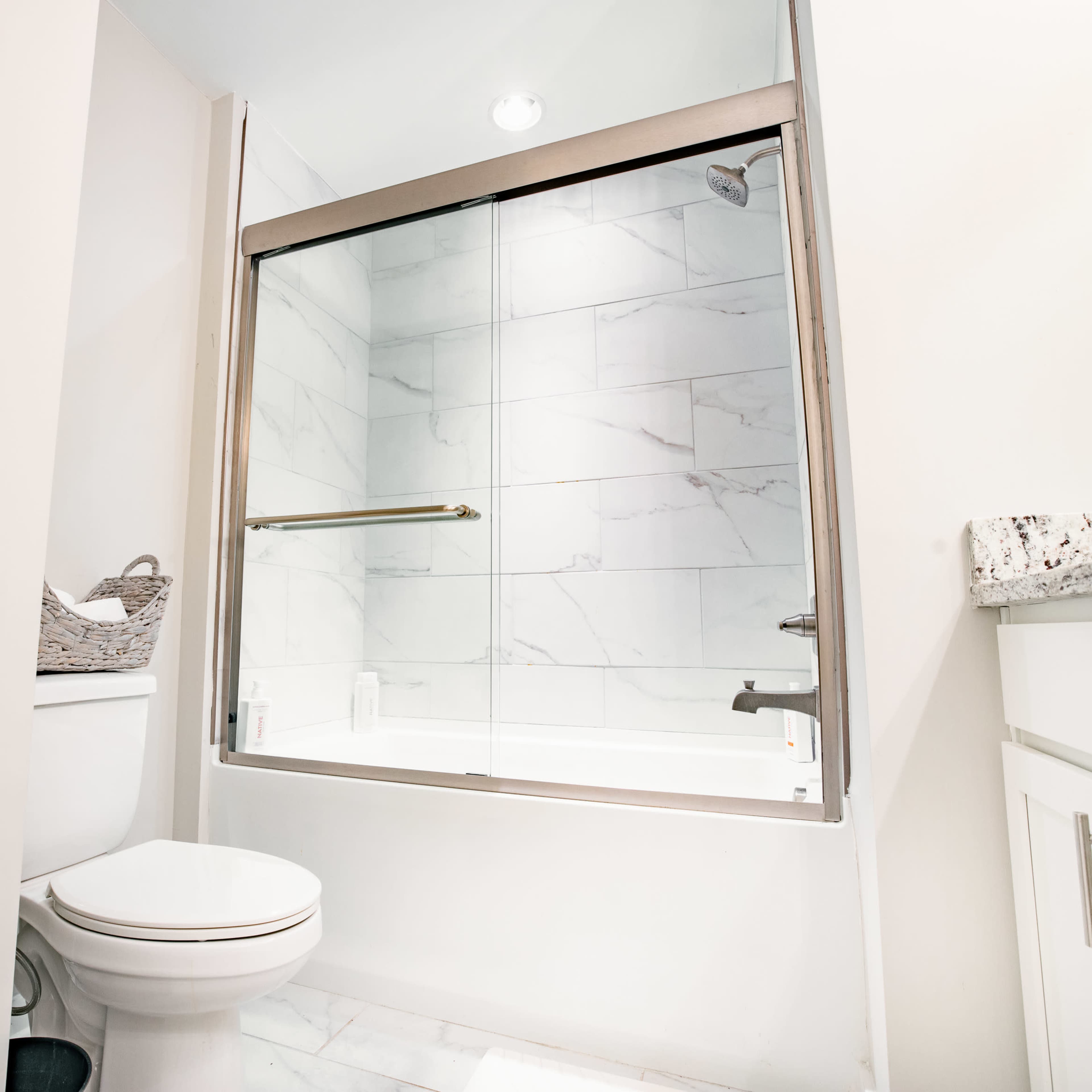 A modern bathroom featuring a glass-enclosed shower, a toilet, and a countertop with white cabinetry.