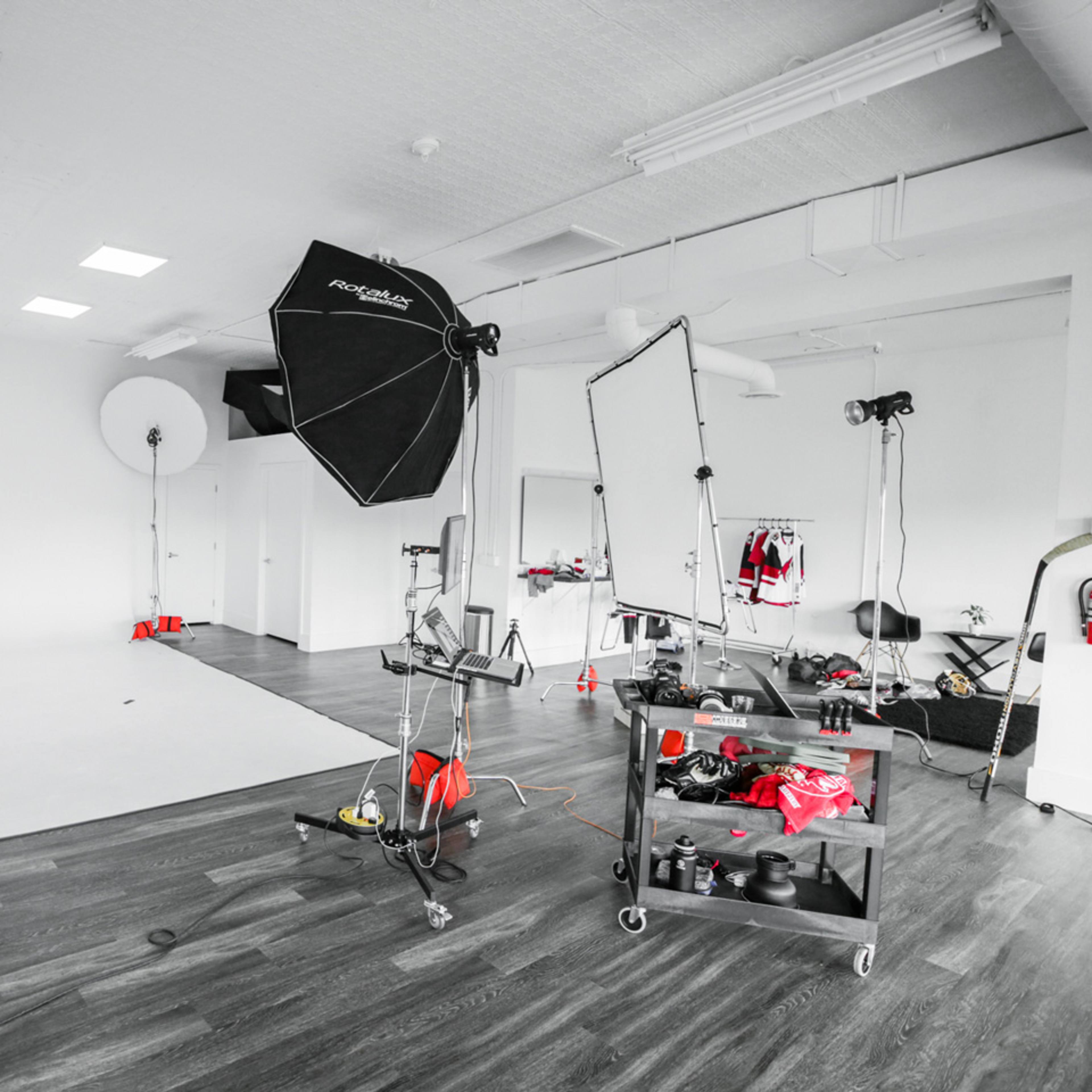 A photography studio is set up with multiple lighting equipment, a backdrop, and various props organized on a cart.