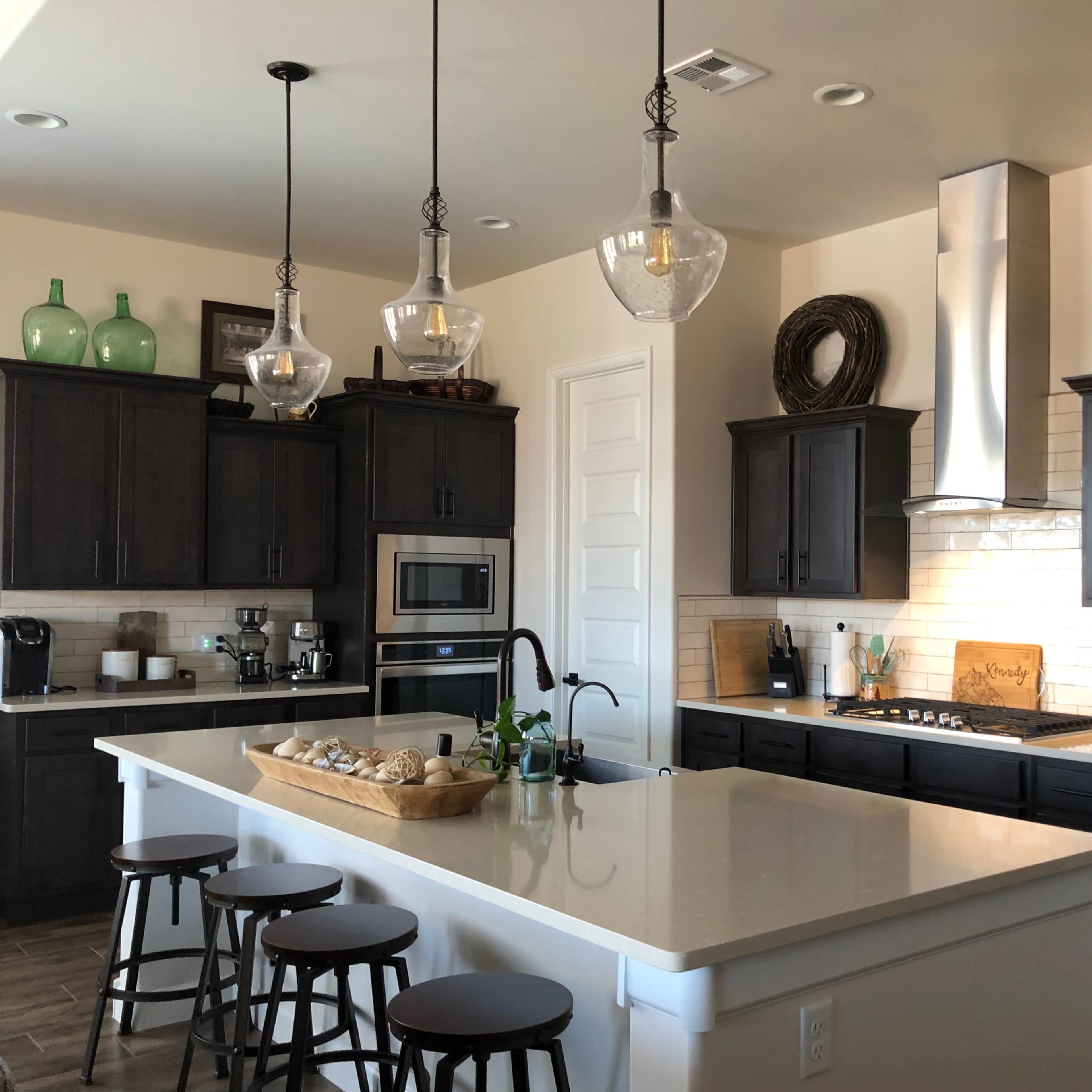 A modern kitchen featuring dark wooden cabinets, a central island with a basket of bread, and stainless steel appliances.