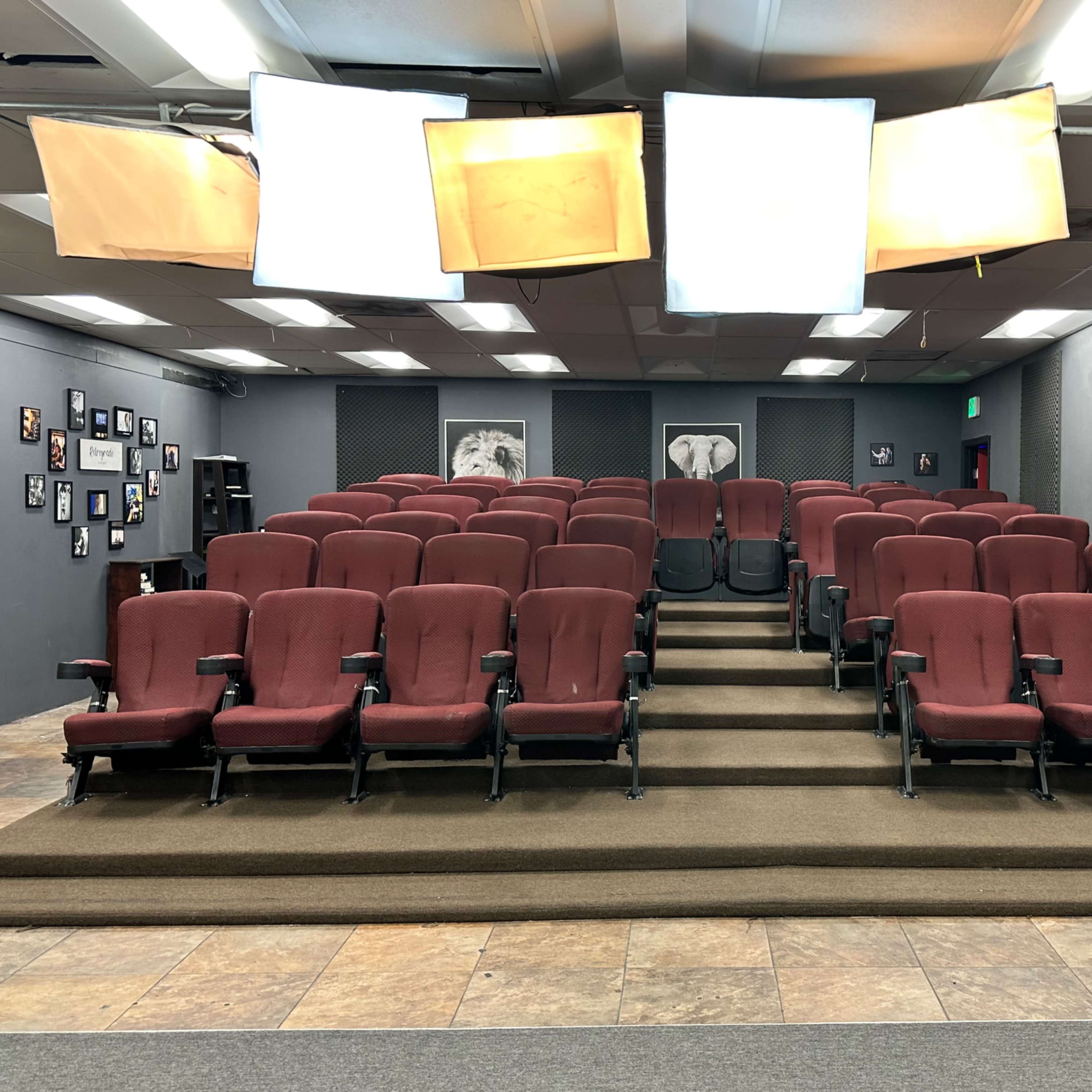 A small theater with red seats arranged in rows on a raised platform, surrounded by dark walls and ambient lighting.