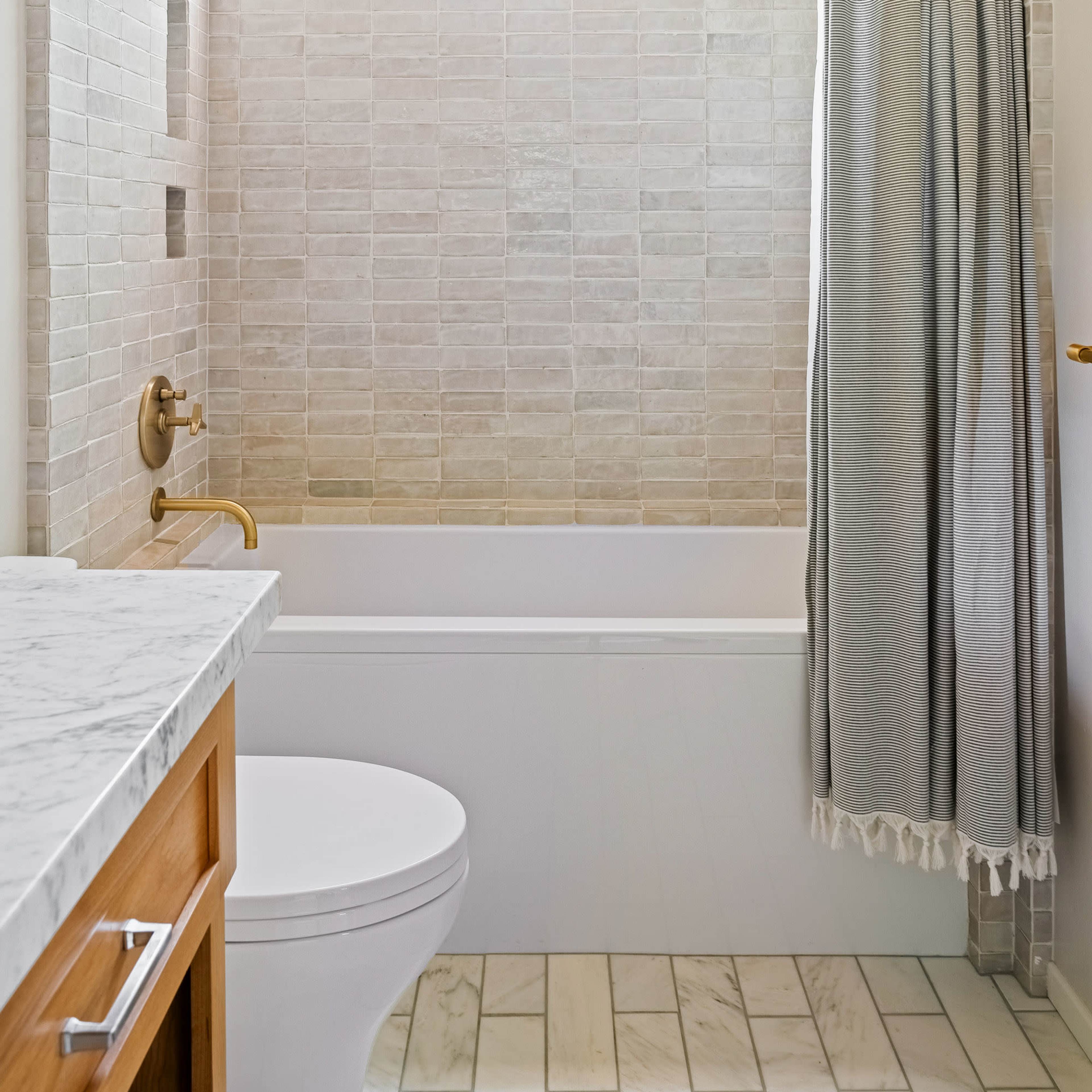 A bathroom featuring a bathtub with a shower curtain, a marble countertop, and a window above the tub.