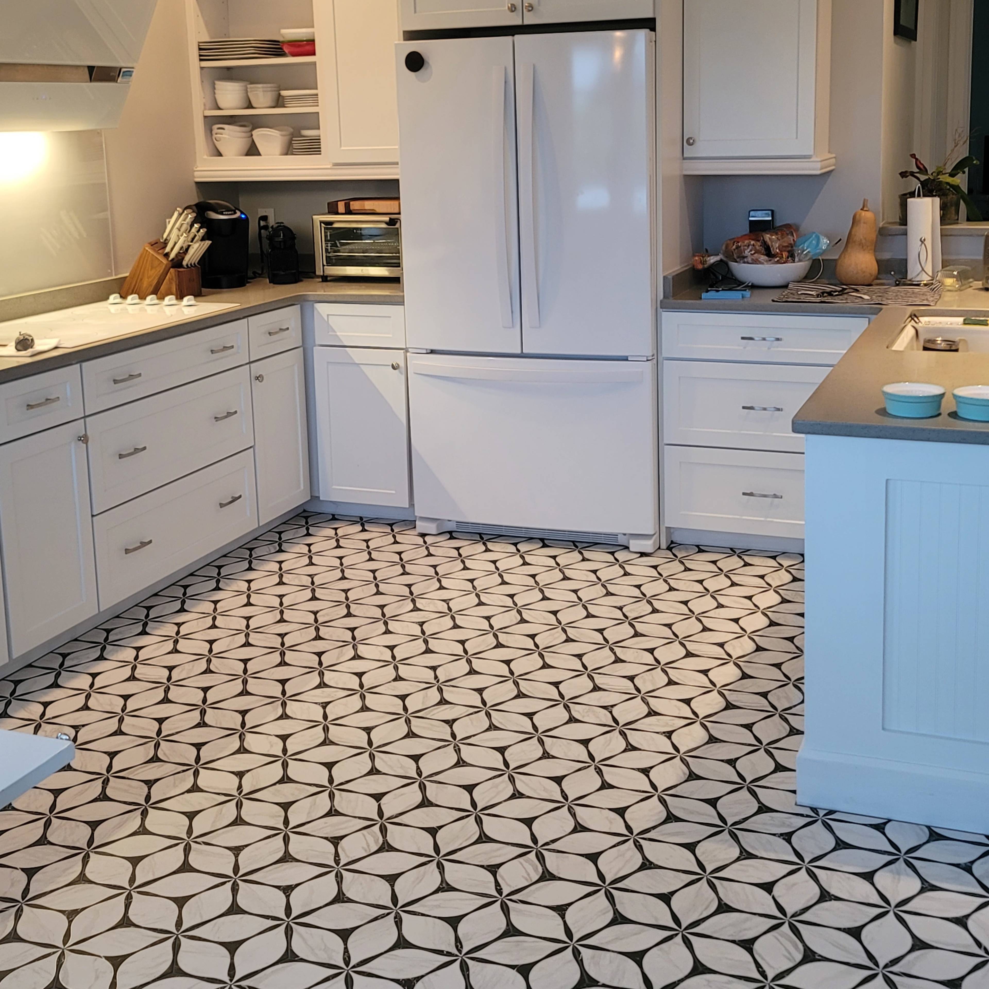The kitchen features white cabinets, a large refrigerator, and a black-and-white patterned tile floor.