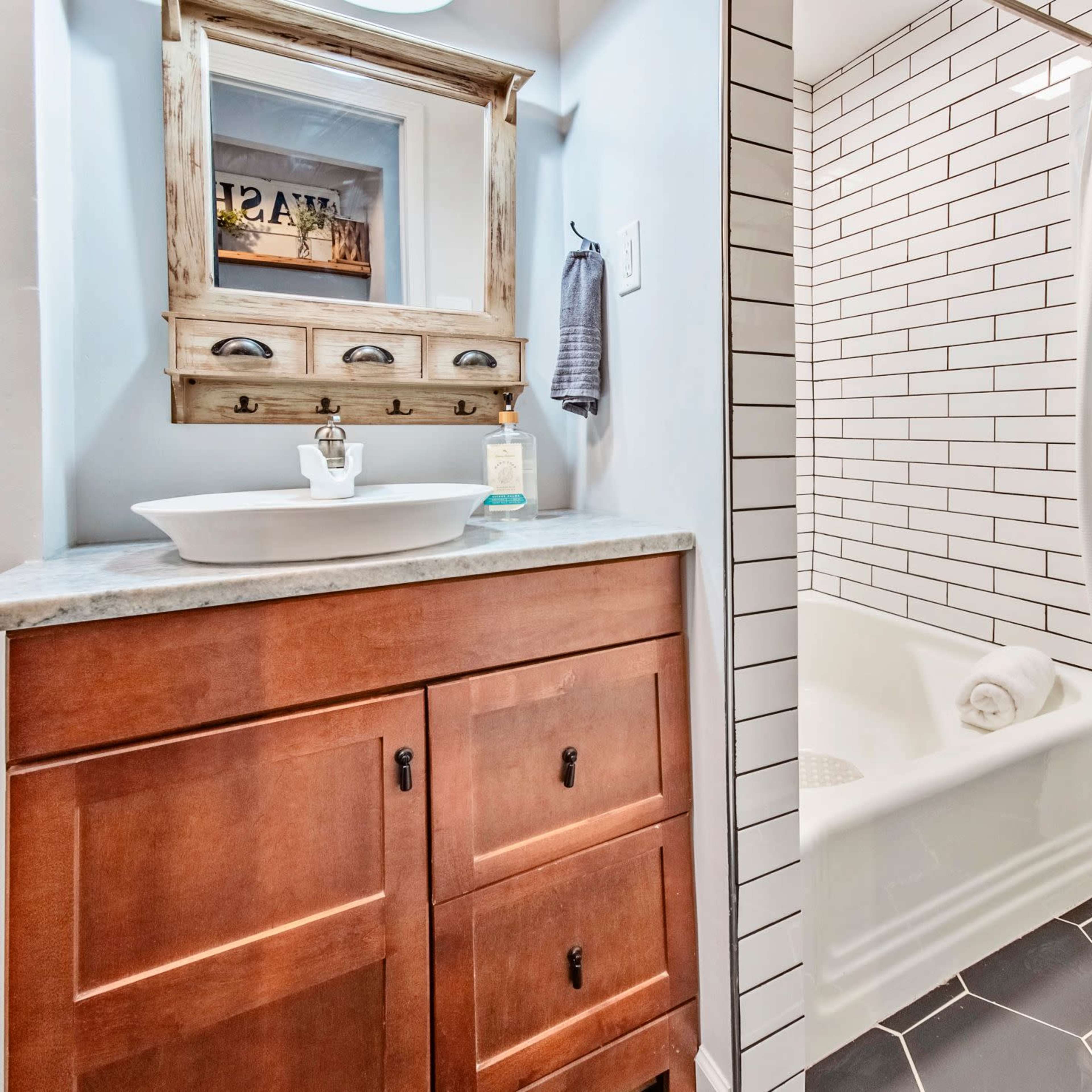 A bathroom featuring a wooden vanity with a sink, a bathtub with a shower curtain, and tiled walls.