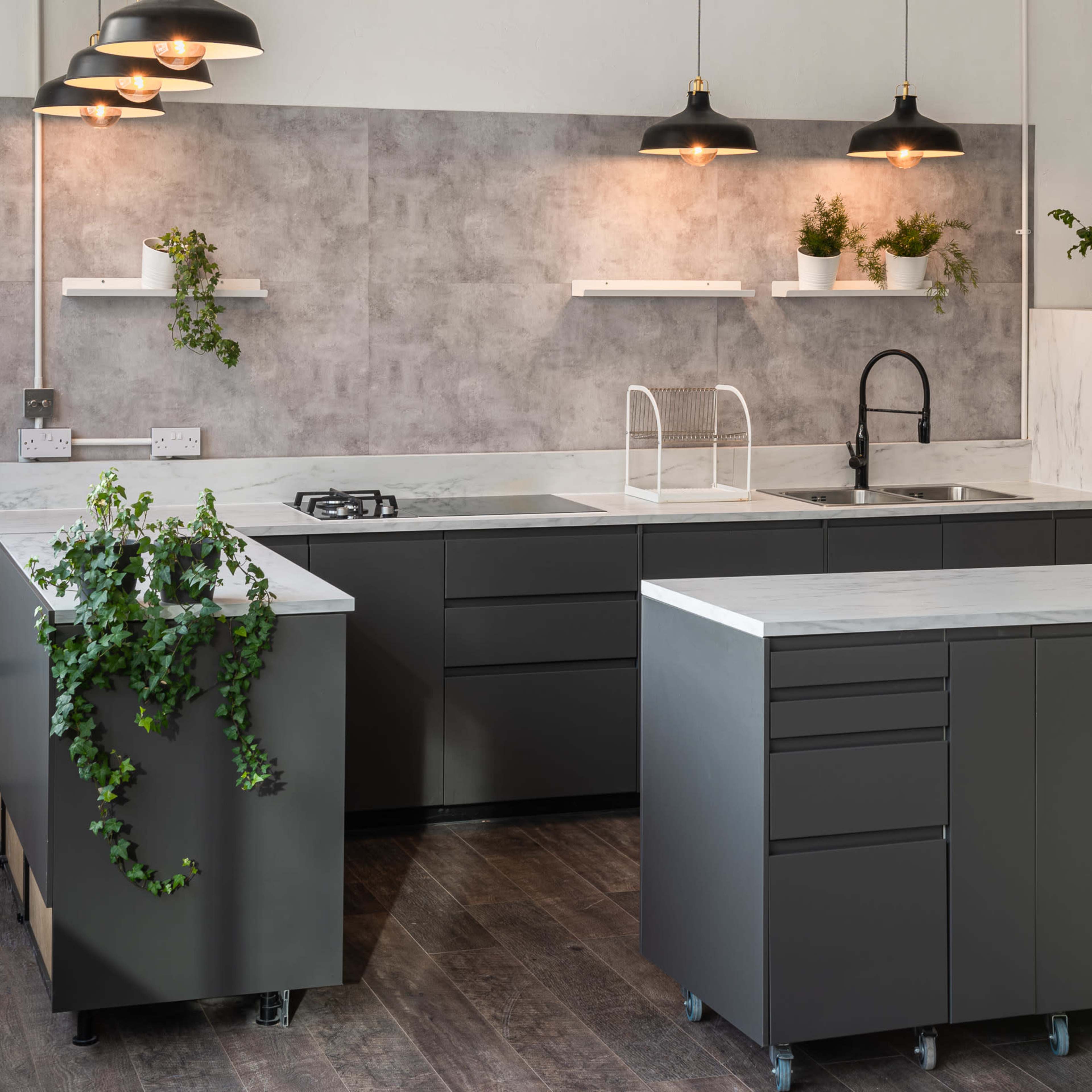 The modern kitchen features gray cabinetry, stainless steel appliances, and marble countertops, with pendant lighting and decorative plants on the walls.