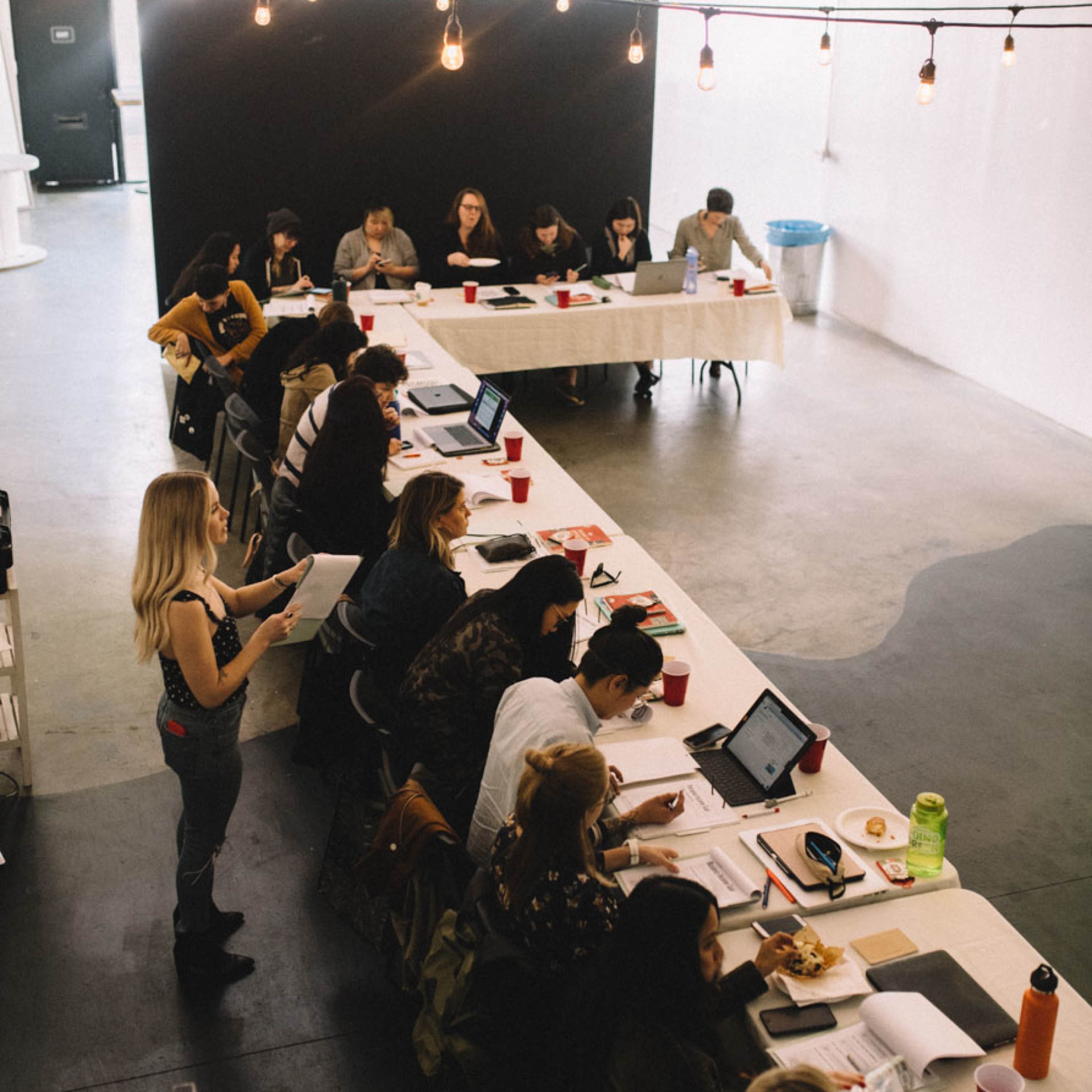 A group of people is studying and working at tables in a well-lit, modern room.