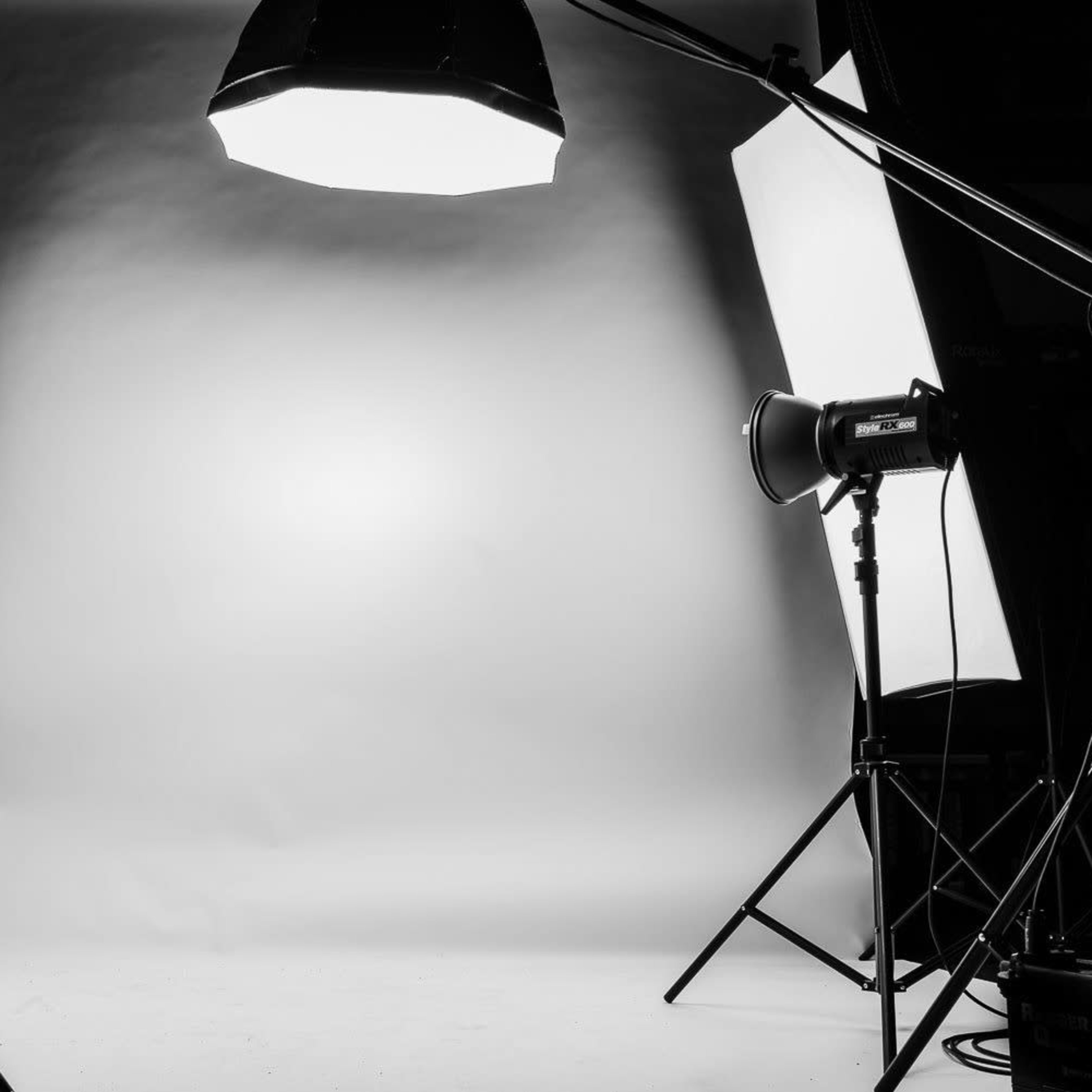 A photo studio setup with two softbox lights positioned on either side of a white backdrop.