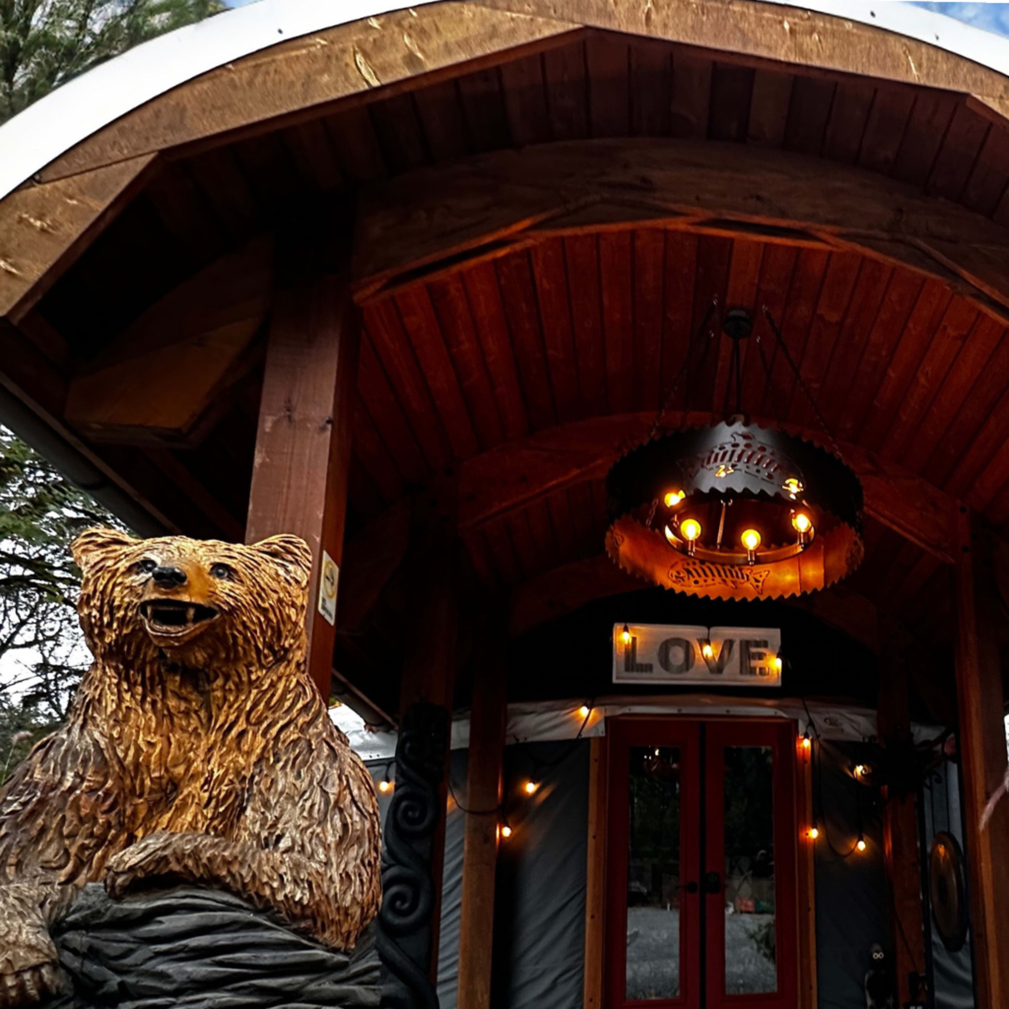 The entrance features a wooden archway with a bear sculpture on the side and a chandelier above a door marked with the word "LOVE."