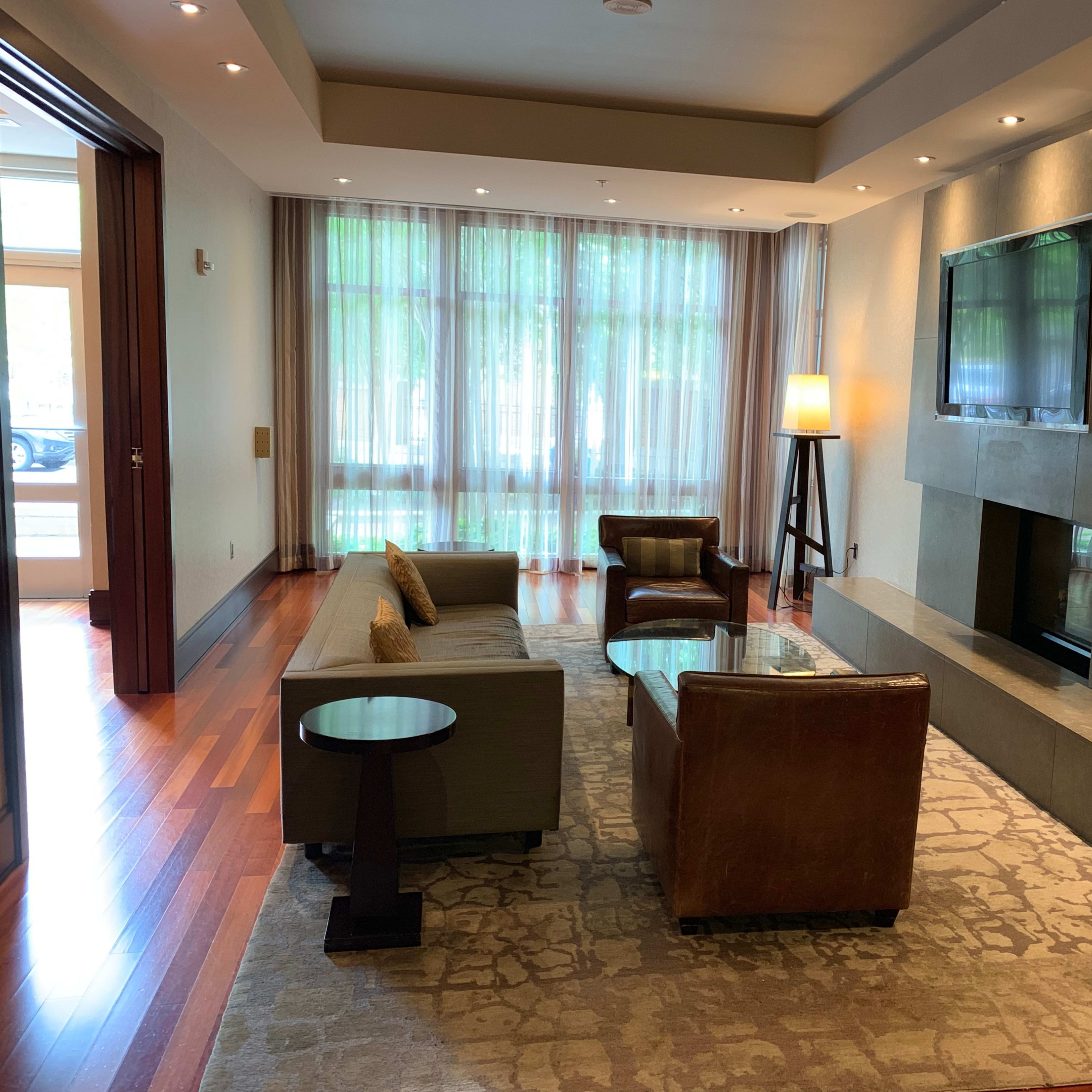 A modern living room with a sofa, two armchairs, a coffee table, and a large wall-mounted television above a stone fireplace.