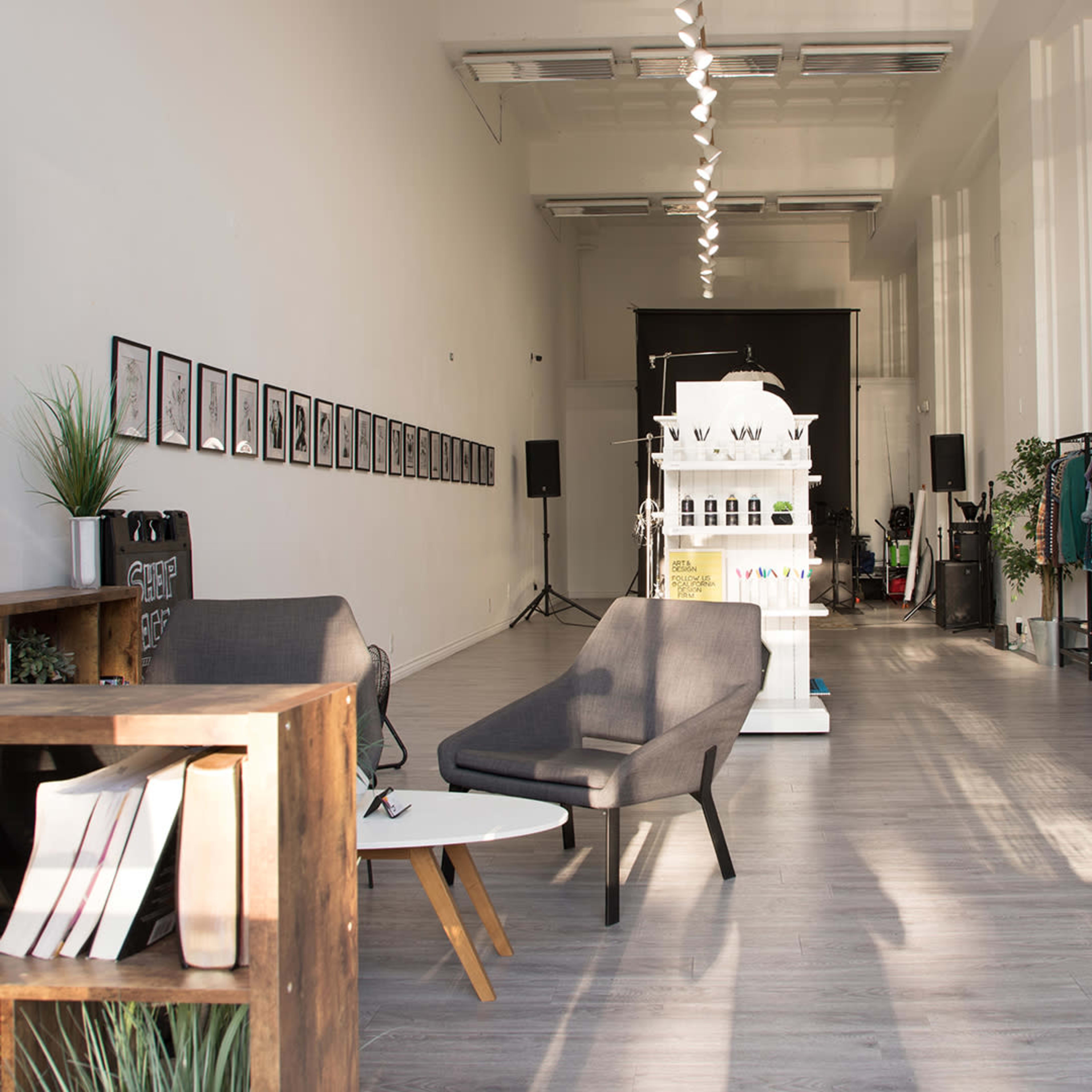 A spacious interior of a design studio featuring modern furniture, framed artwork on the walls, and display areas for products.
