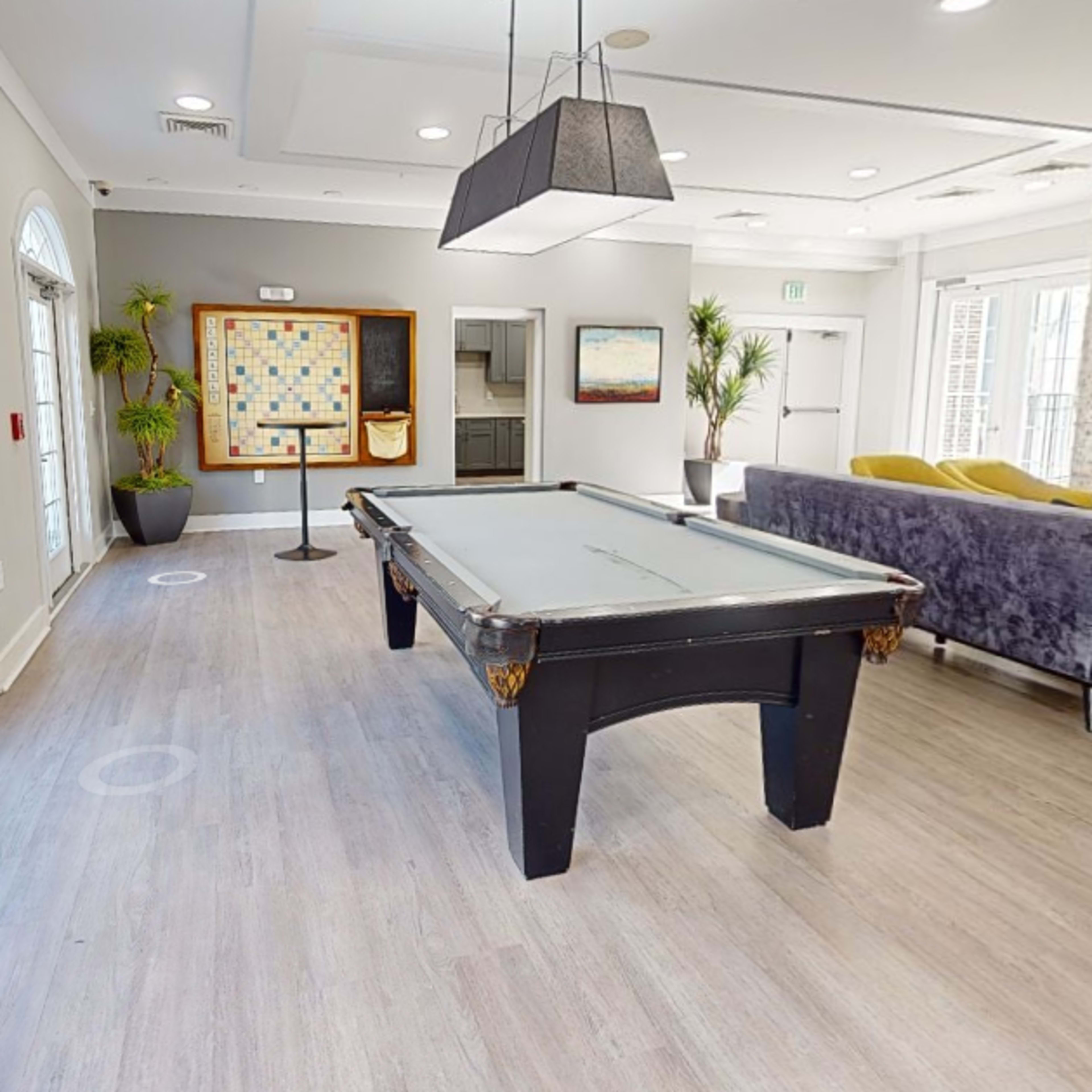 A recreational room with a pool table, seating areas, and a large television against a stone wall.