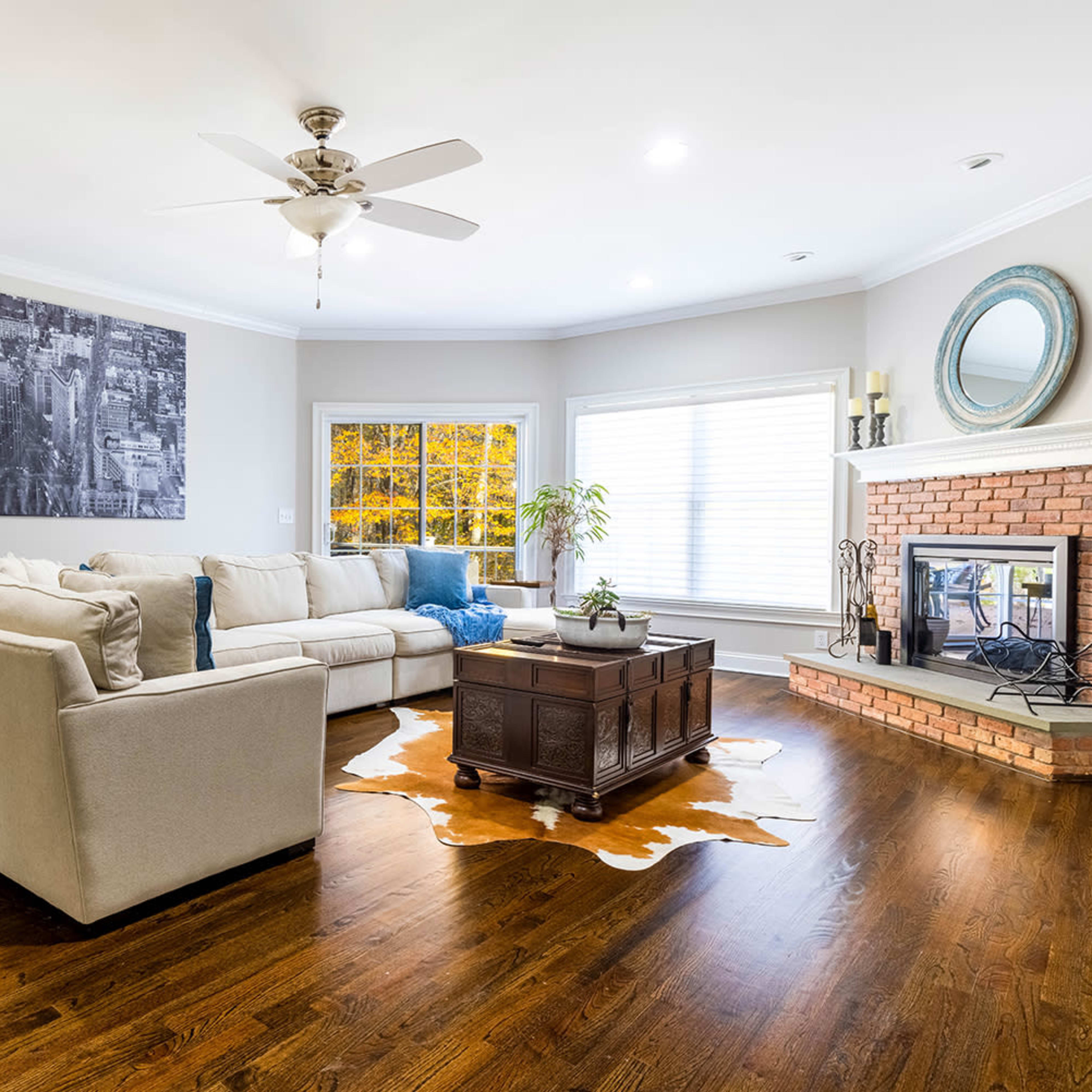 A spacious living room features a large sectional sofa, a coffee table on a cowhide rug, and a fireplace with a decorative mirror above it.