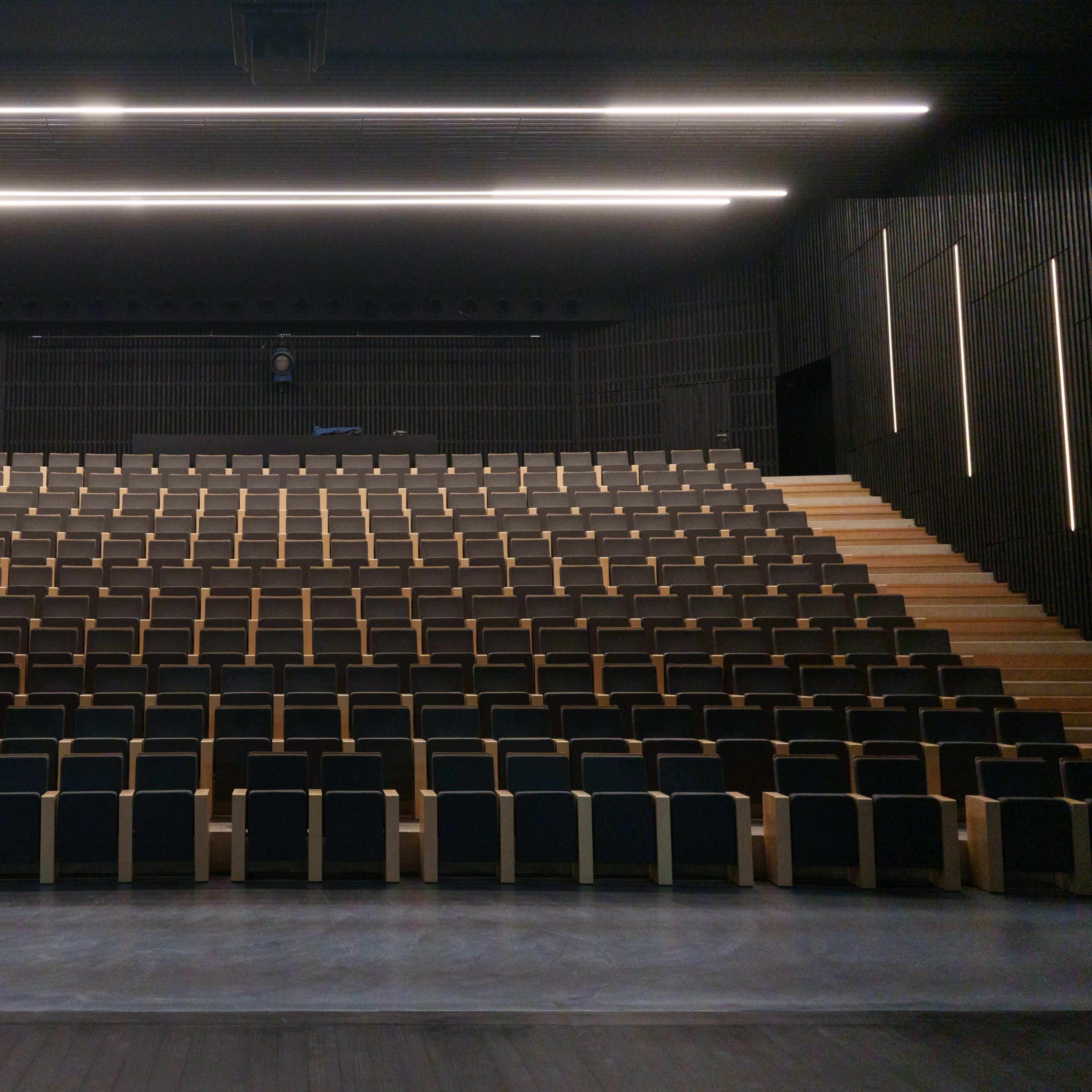 A modern auditorium with tiered seating arranged in a symmetrical layout.