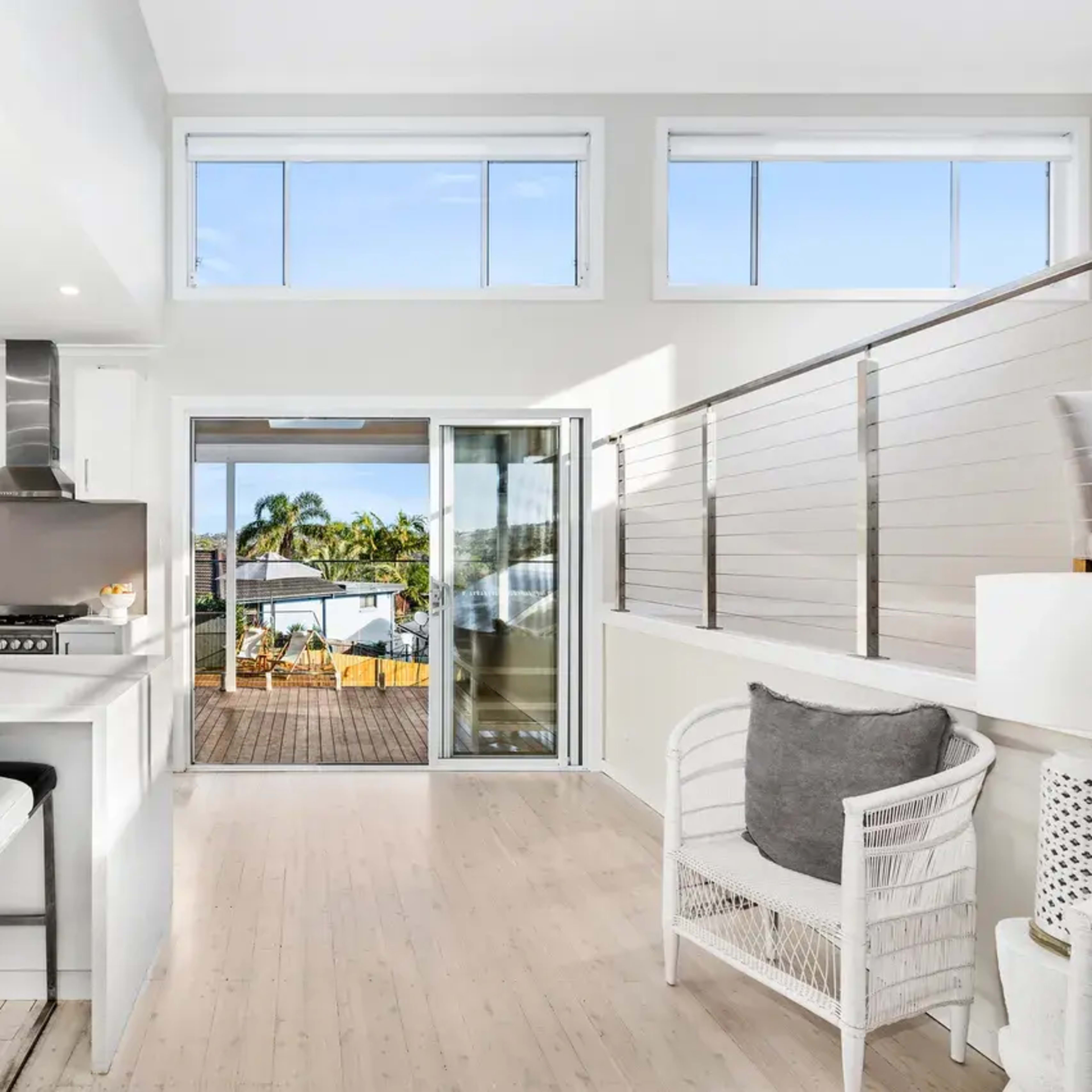 A bright, modern kitchen with white cabinetry and a view of a deck through sliding glass doors.