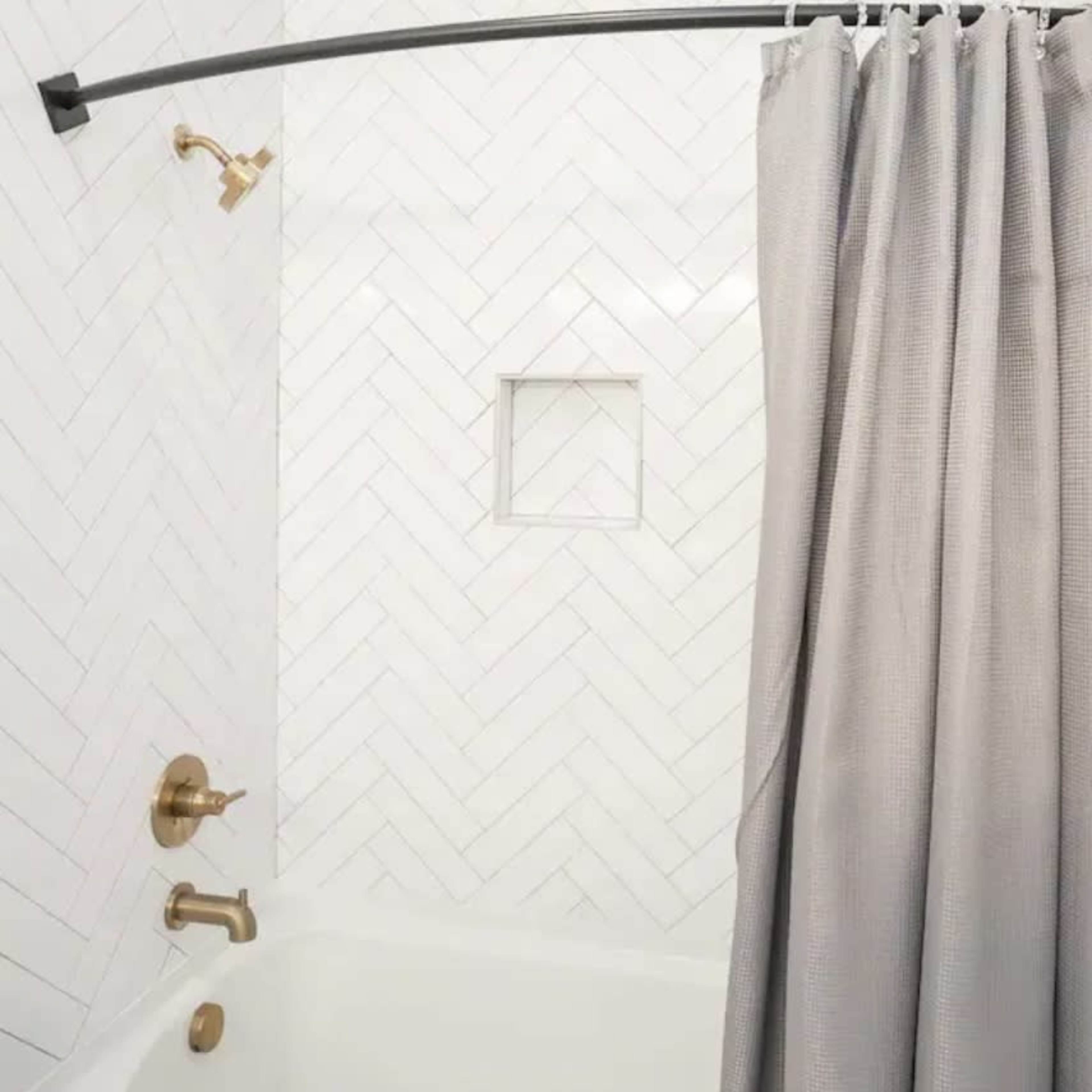 A bathroom featuring a bathtub with a shower curtain, a wall with herringbone tiled design, and a wall-mounted showerhead.