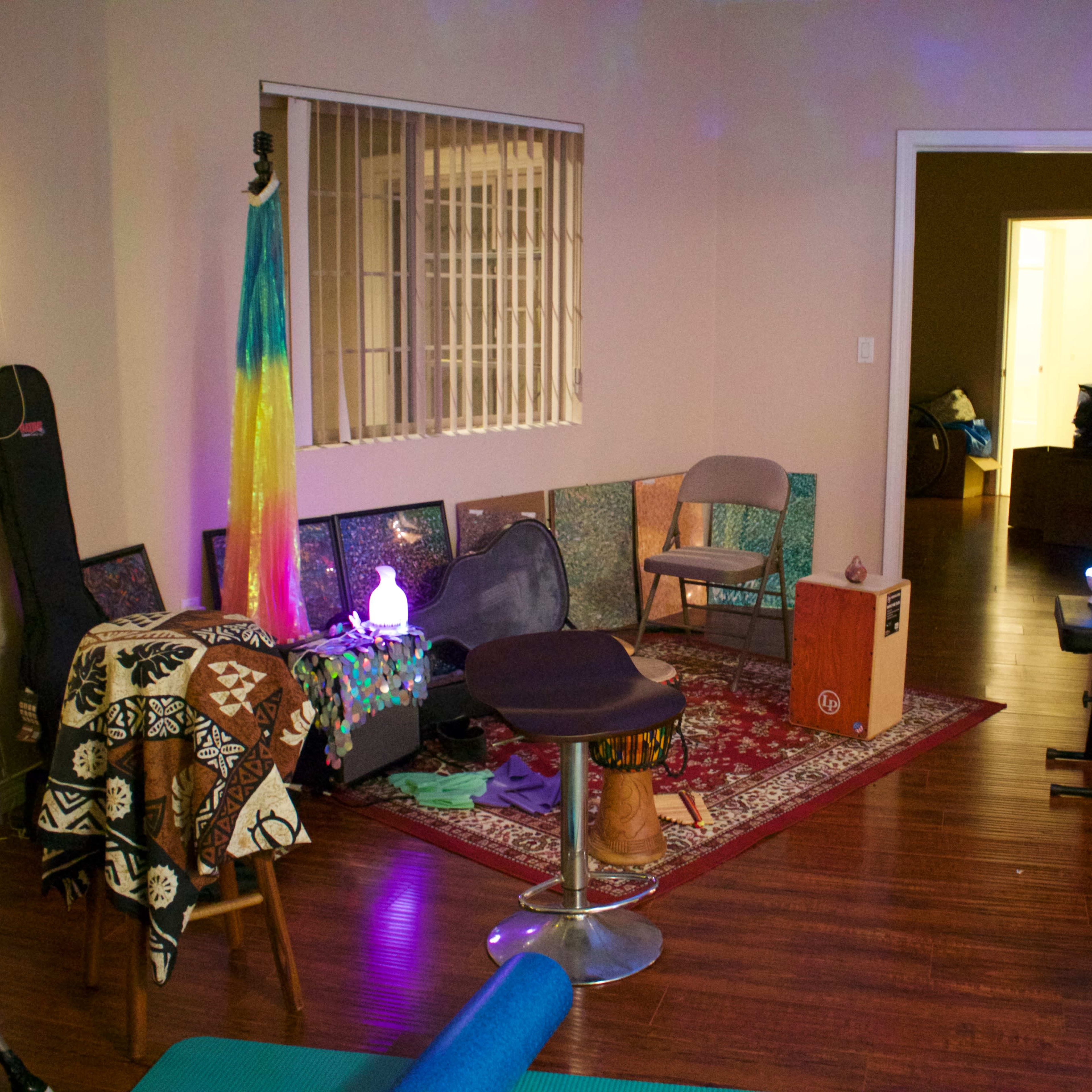 The room features a mix of seating options, musical instruments, and decorative elements, with a soft glow from lights in the corner.