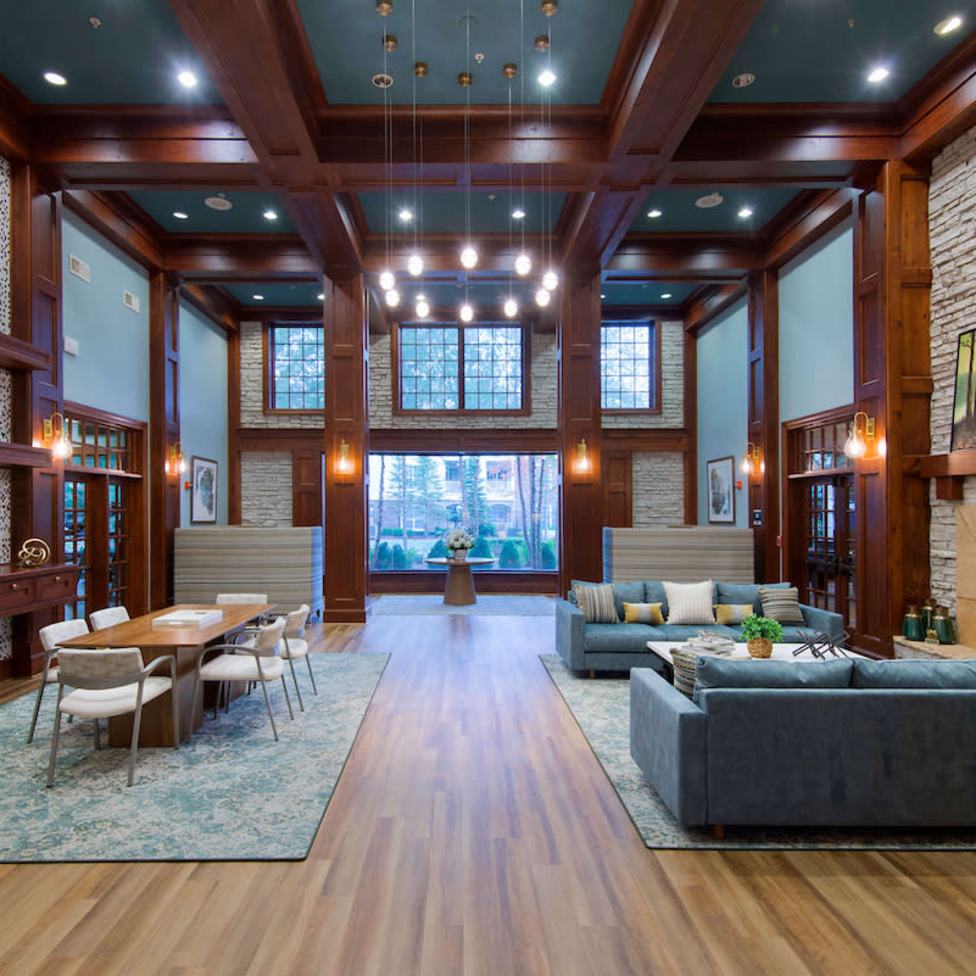 A spacious living area featuring a dining table, a comfortable seating arrangement, large windows, and a stone fireplace.