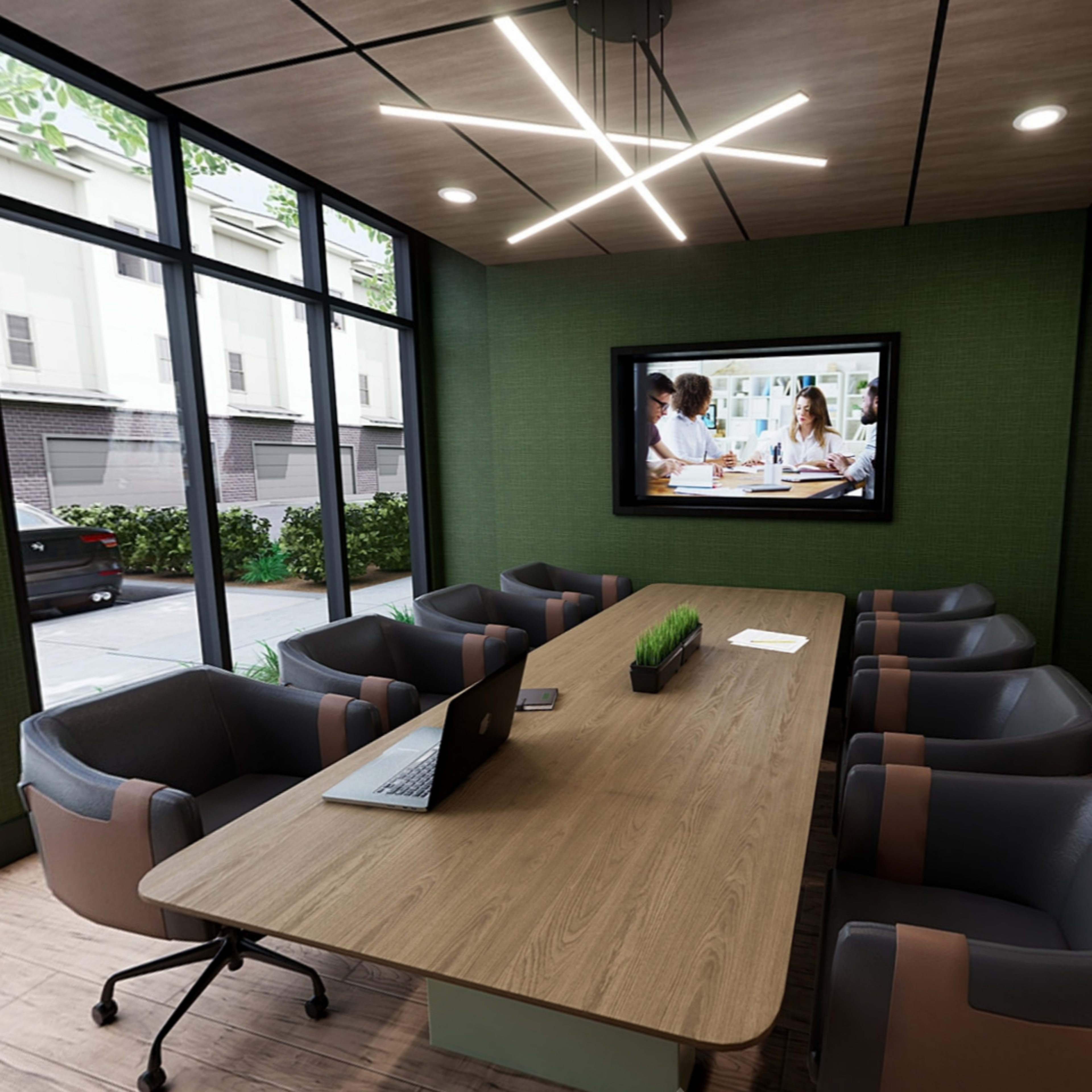 A modern conference room features a large wooden table, gray chairs, a laptop, and a TV displaying a group of people in a meeting, with large windows providing a view of the exterior.