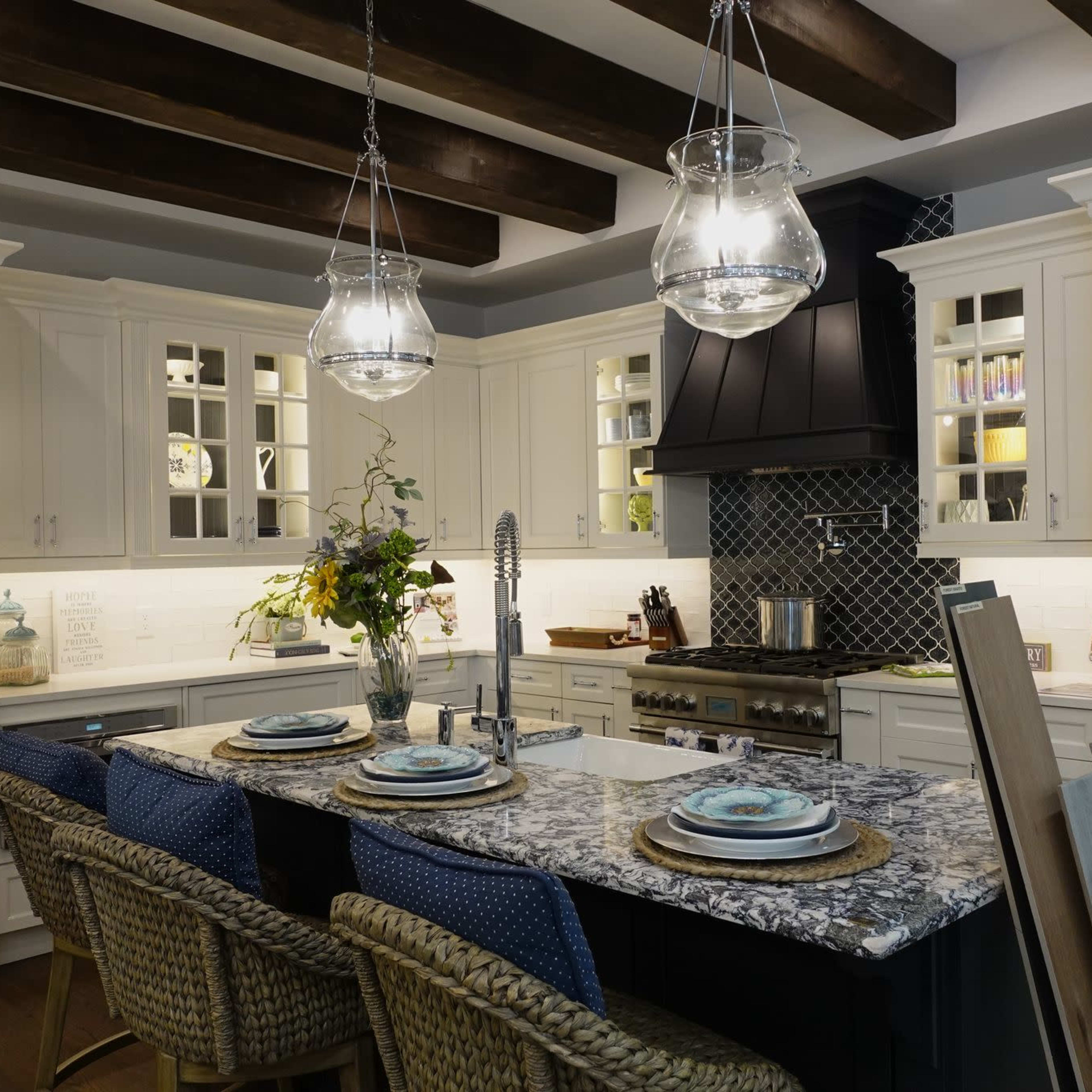 A modern kitchen with white cabinetry, a central island with a patterned countertop, and pendant lighting above.