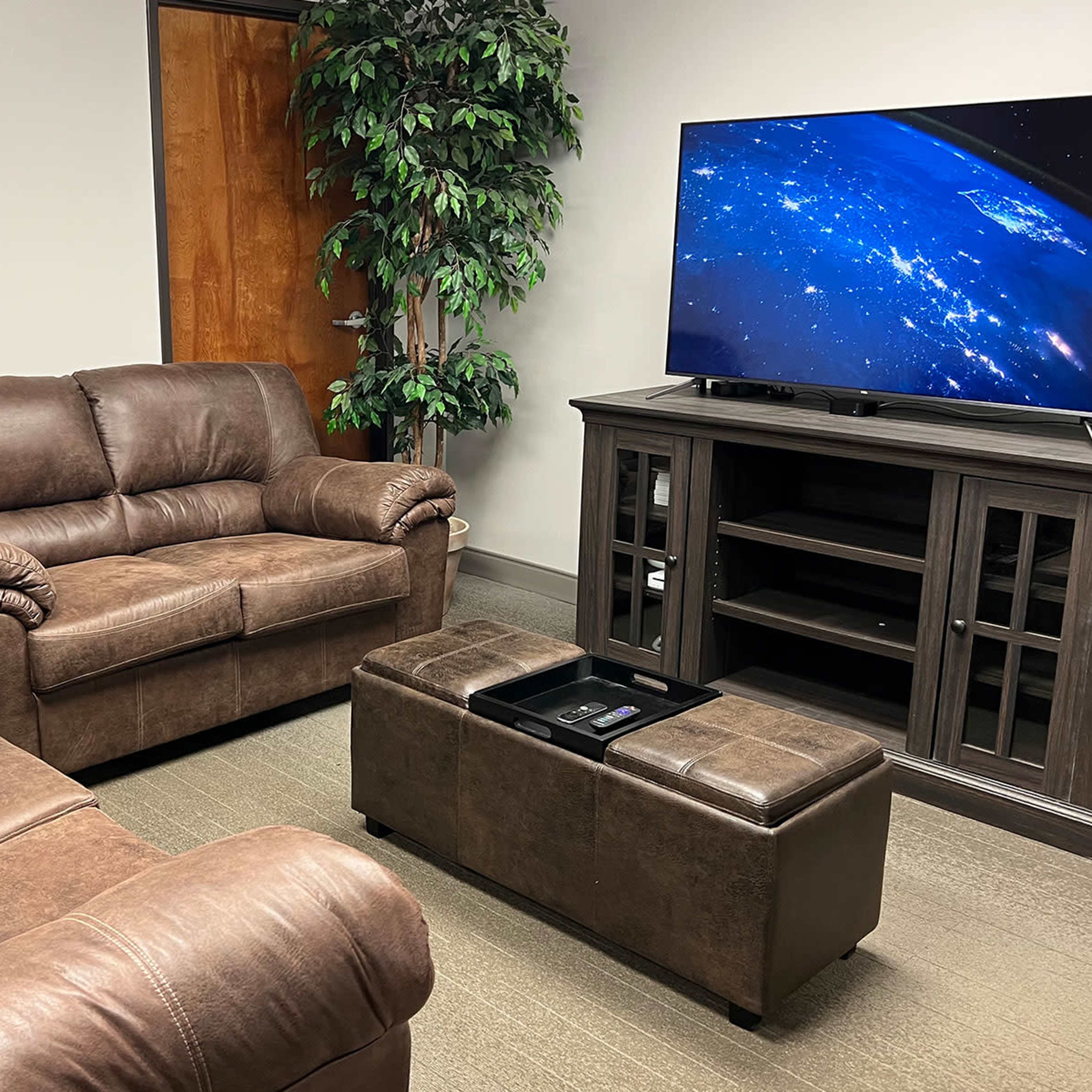 A small room furnished with two brown sofas, a coffee table, and a television mounted on a cabinet.