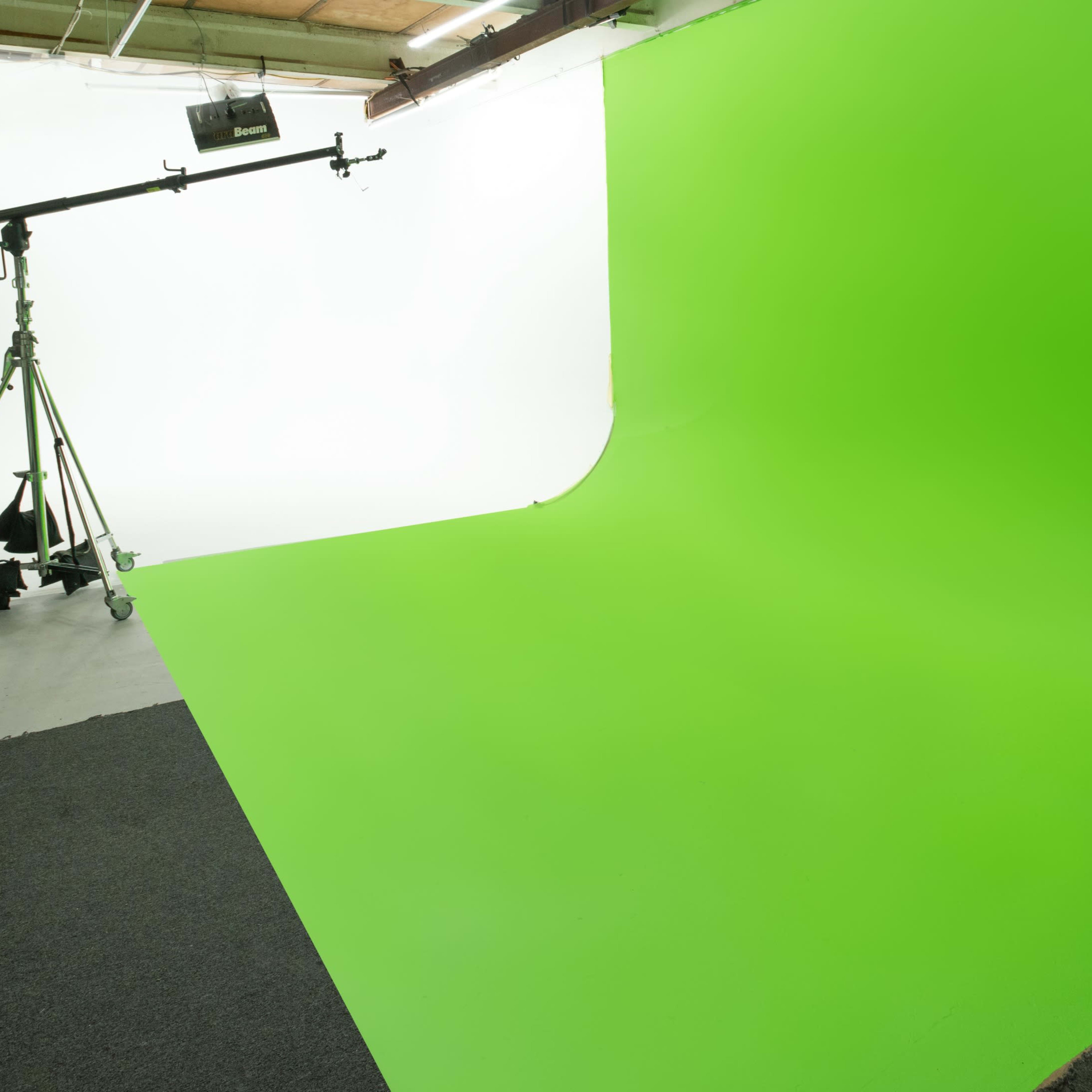 A photography studio with a green screen backdrop and a lighting setup on a tripod.