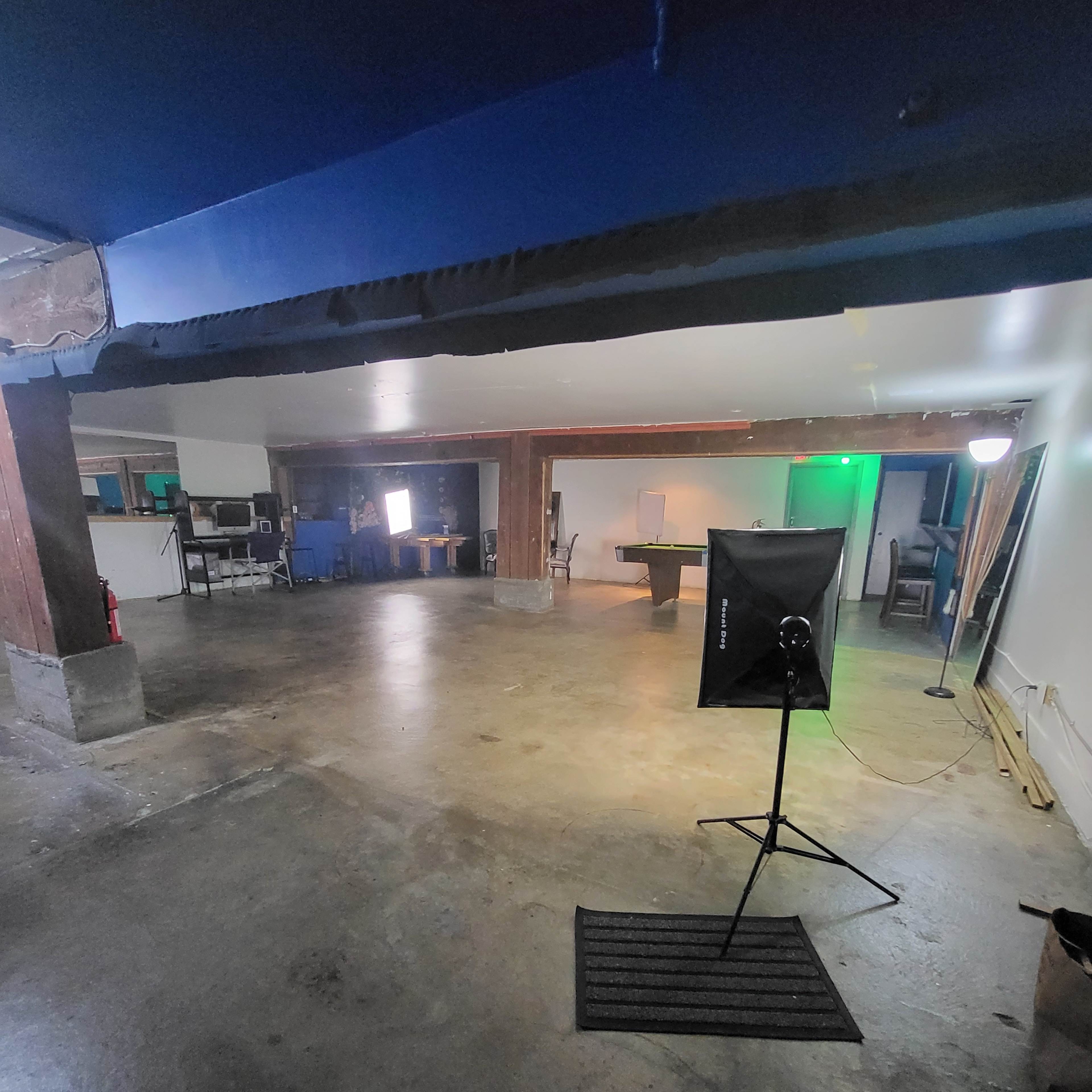 A spacious, empty room with polished concrete floors, wooden beams, and several pieces of furniture visible in the background.