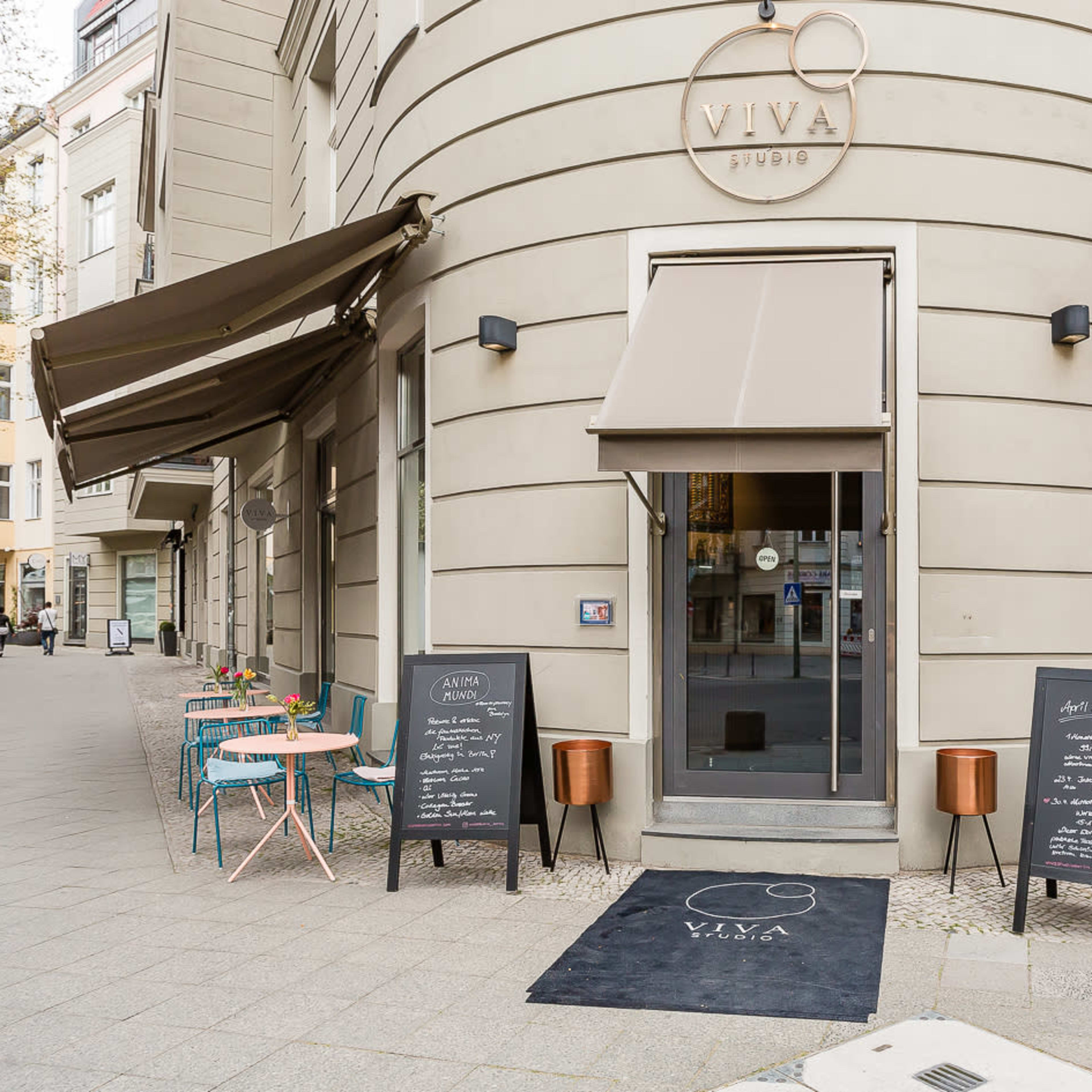 A corner café with outdoor seating, featuring colorful chairs and menus displayed on chalkboards at the entrance.