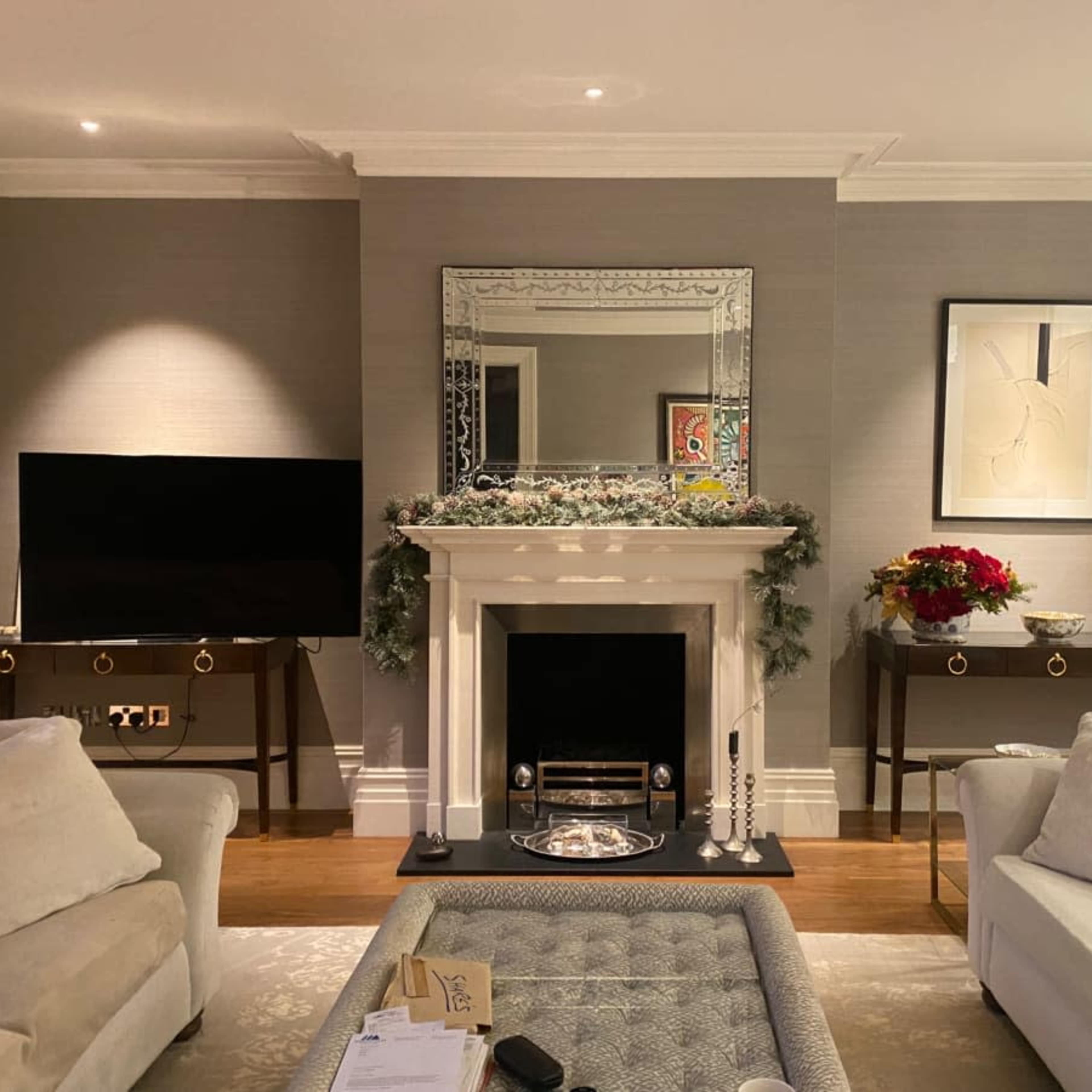 A cozy living room with a fireplace, a large mirror above it, a television on one side, and two sofas facing a coffee table.