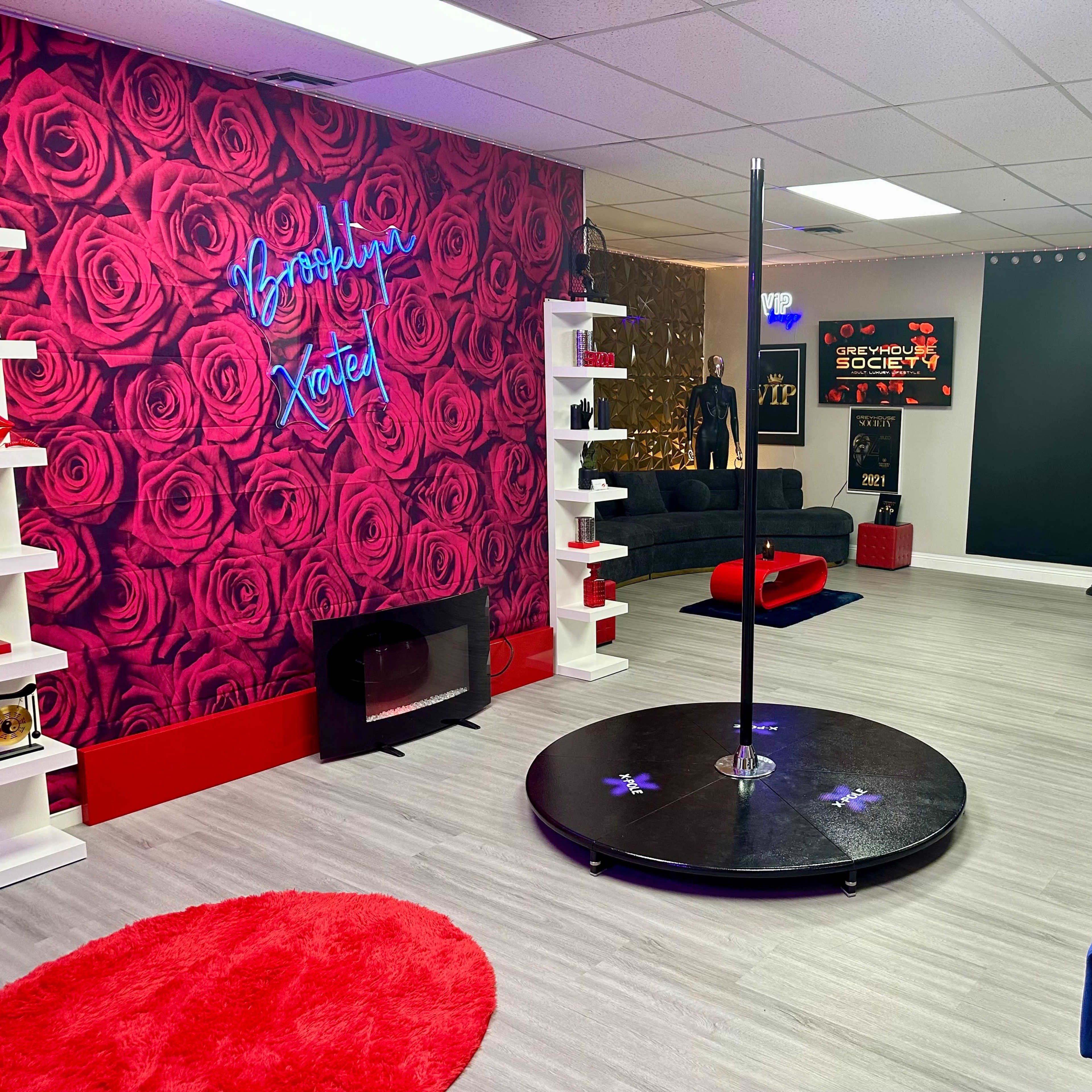 A dance studio featuring a central pole, surrounded by modern furnishings and vibrant wall decor.