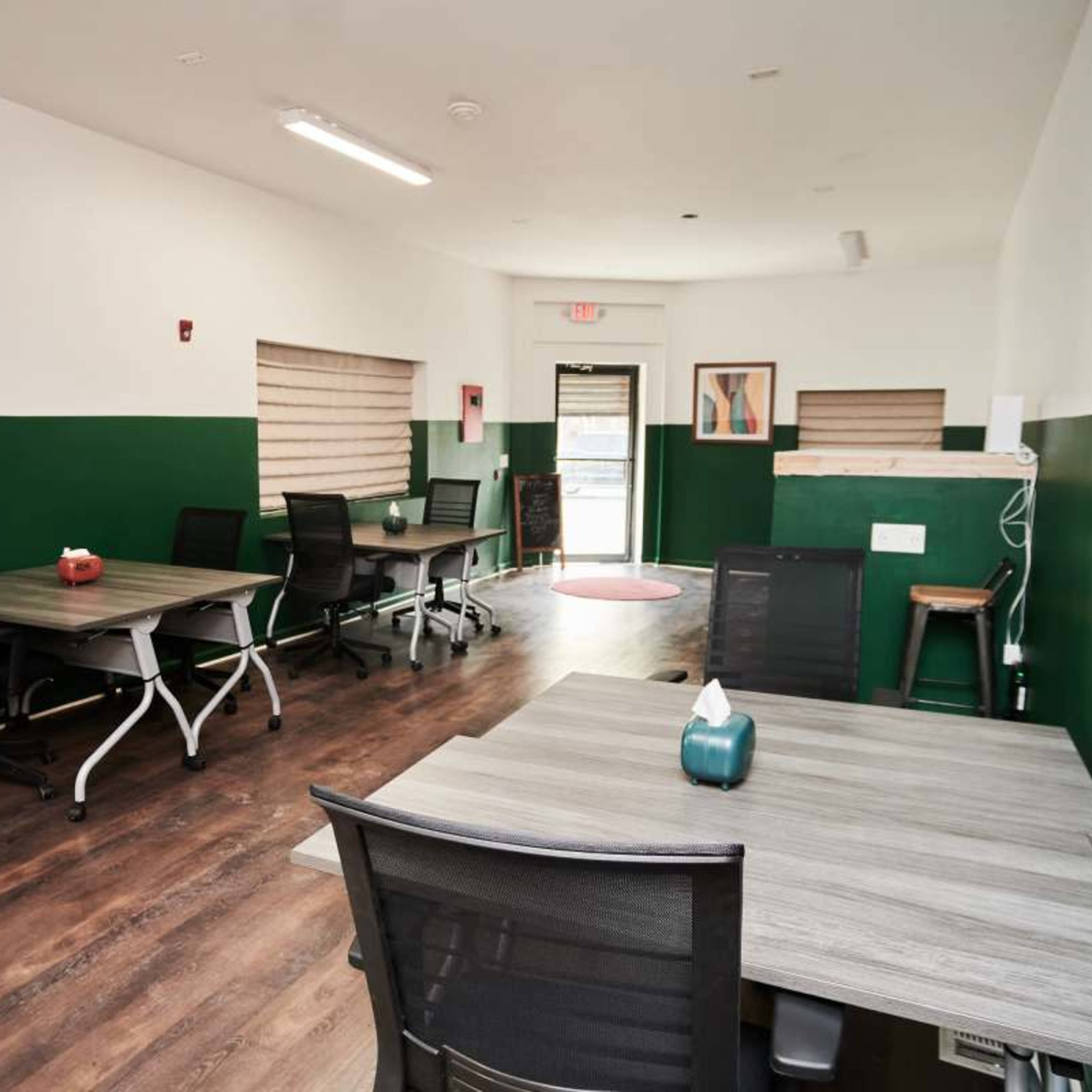 An office space featuring several desks arranged with a green and white color scheme.