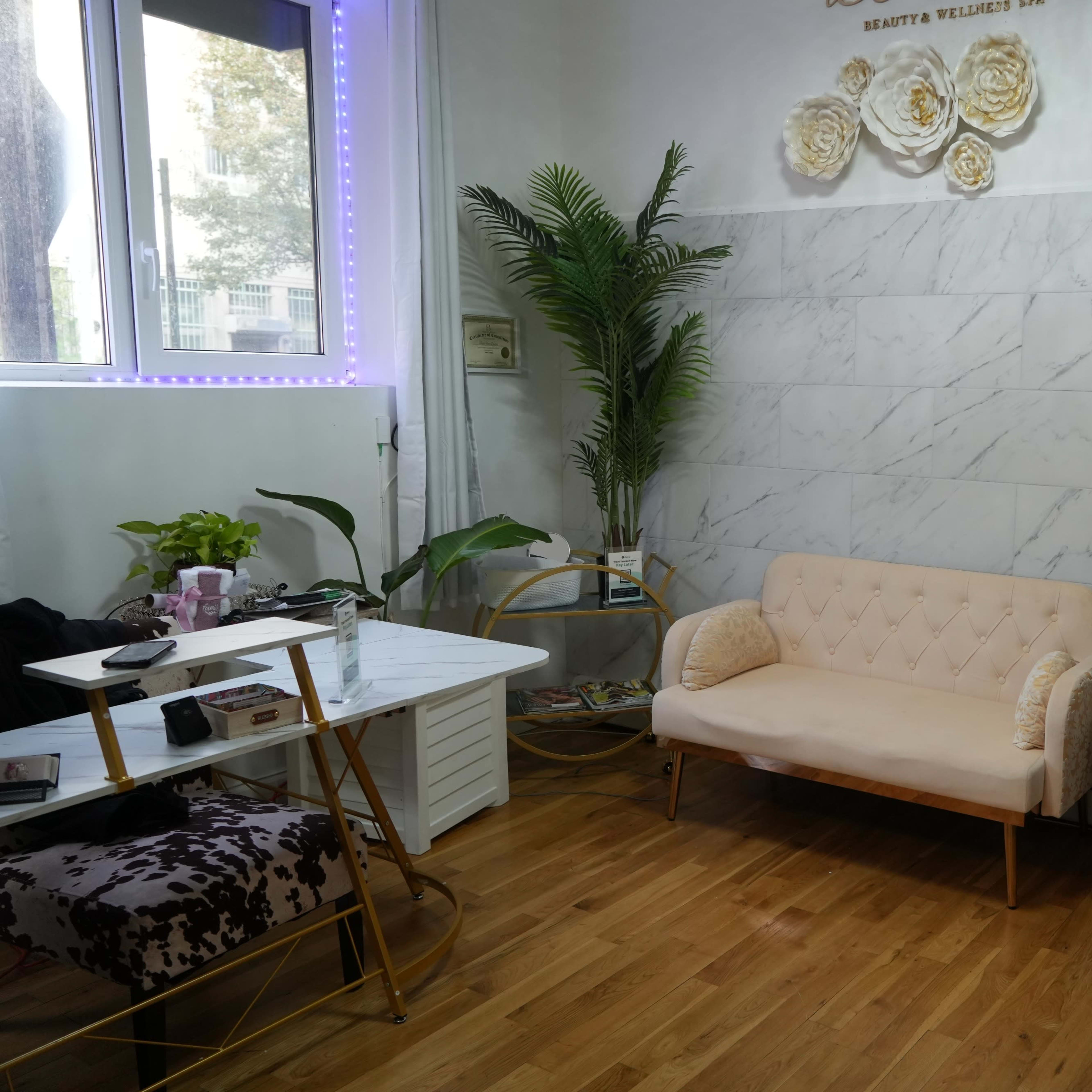 A cozy wellness space featuring a light-colored couch, a small table, a shelf with skincare products, and a decorative plant.