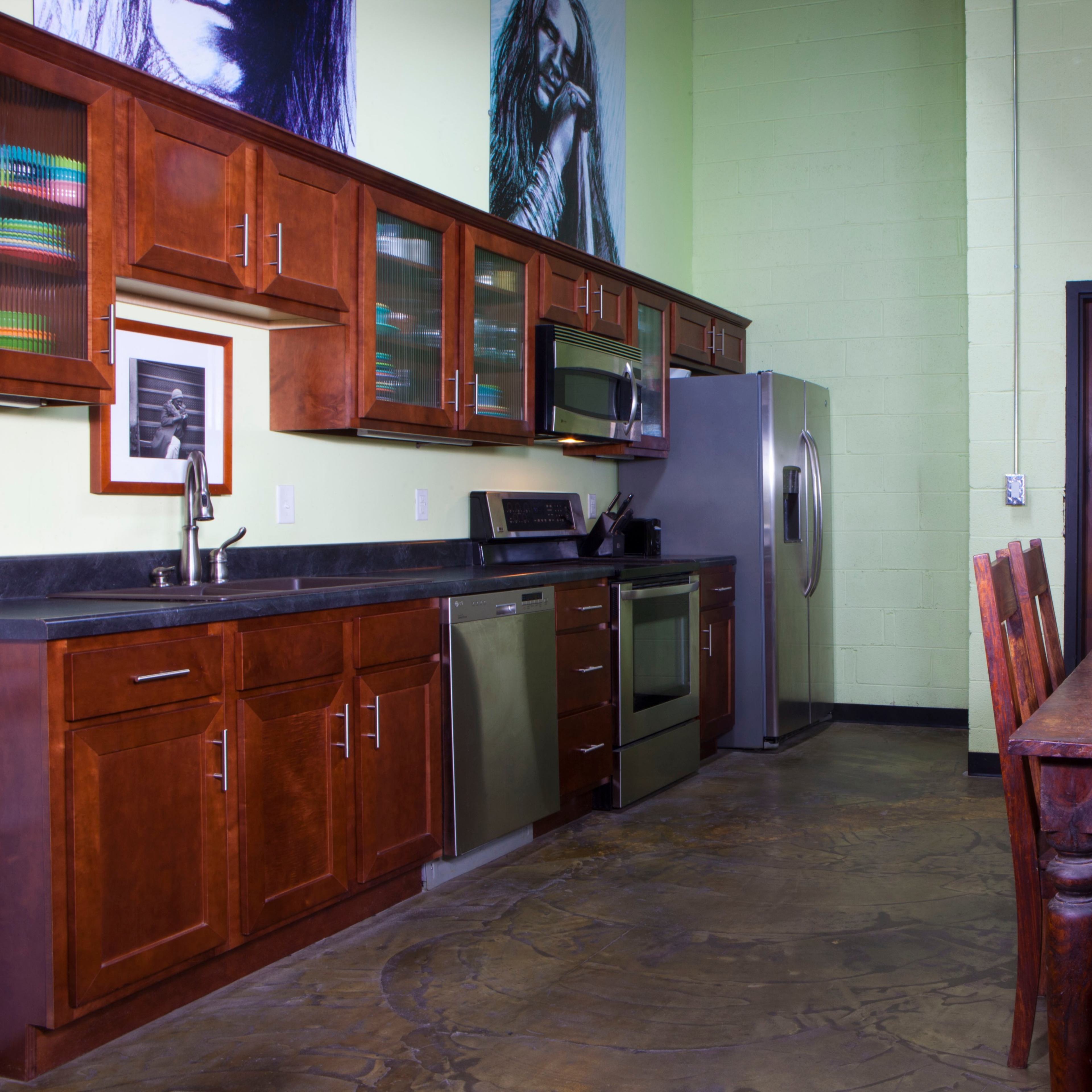 A kitchen with wooden cabinets, stainless steel appliances, and a dining table made of wood, complemented by wicker chairs.