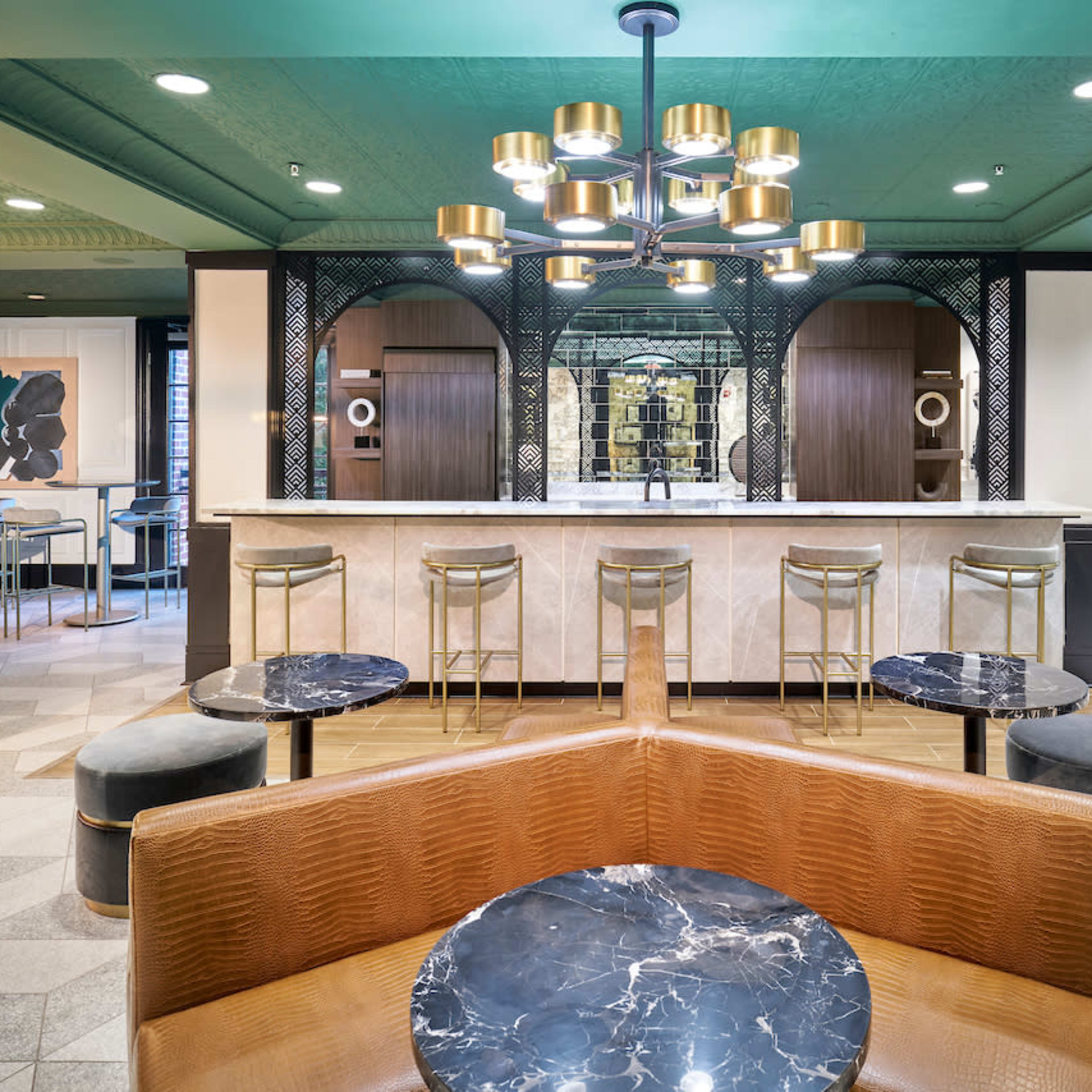 A modern interior of a café or lounge area featuring a marble bar, contemporary seating, and decorative lighting.