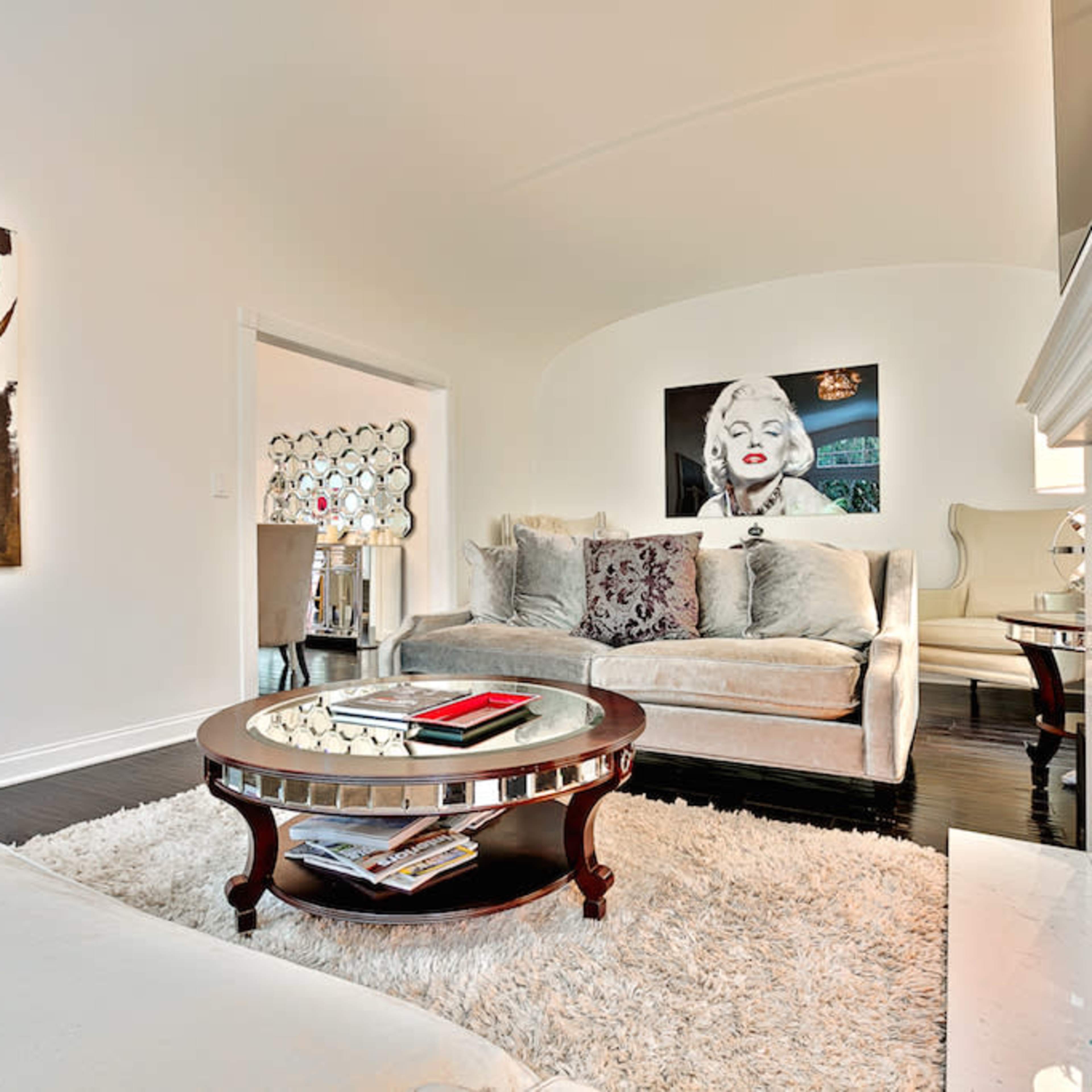 A modern living room with a plush sofa, decorative artwork on the walls, and a cozy fireplace, all set on a soft area rug.