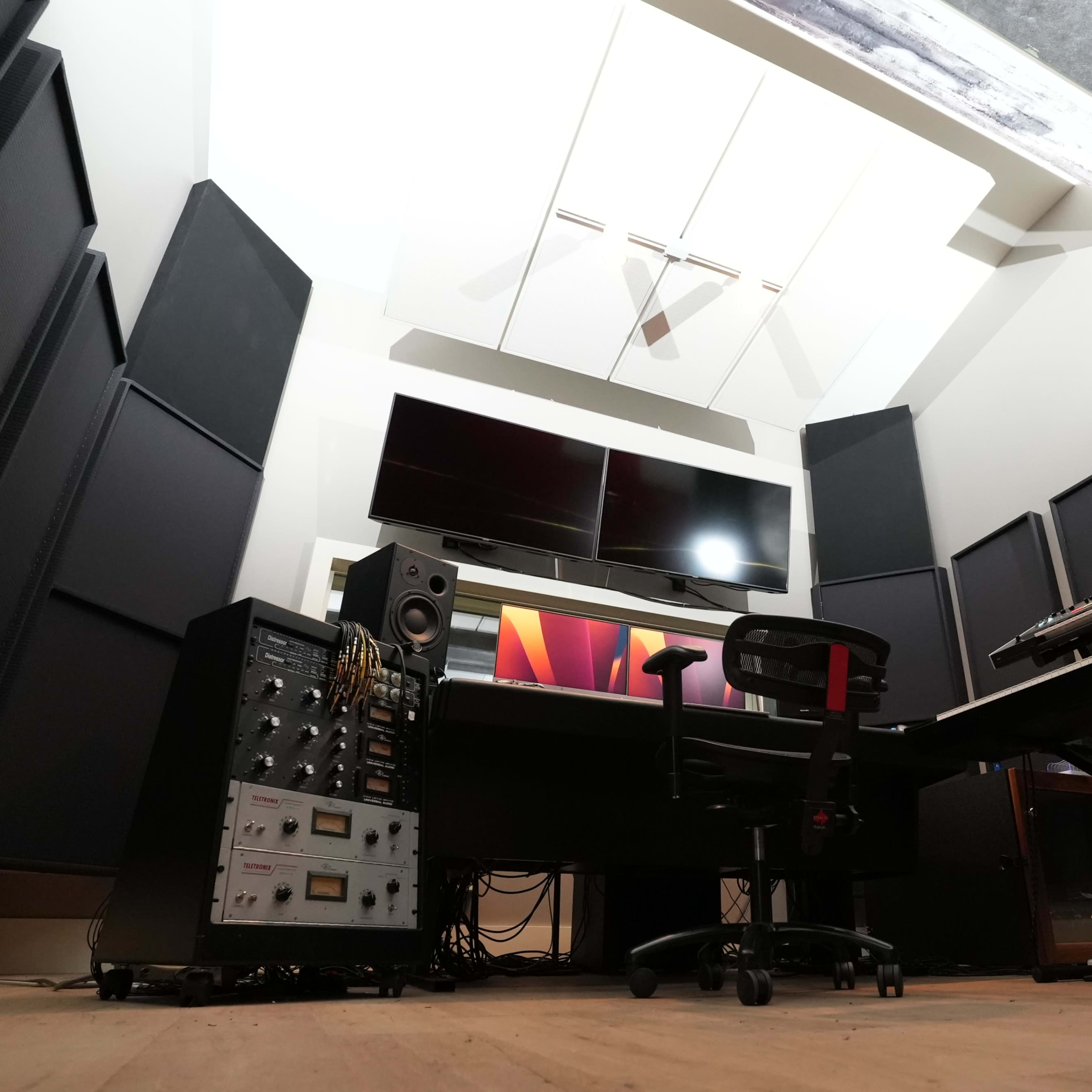A modern music studio with a mixing desk, speakers, and soundproof panels.