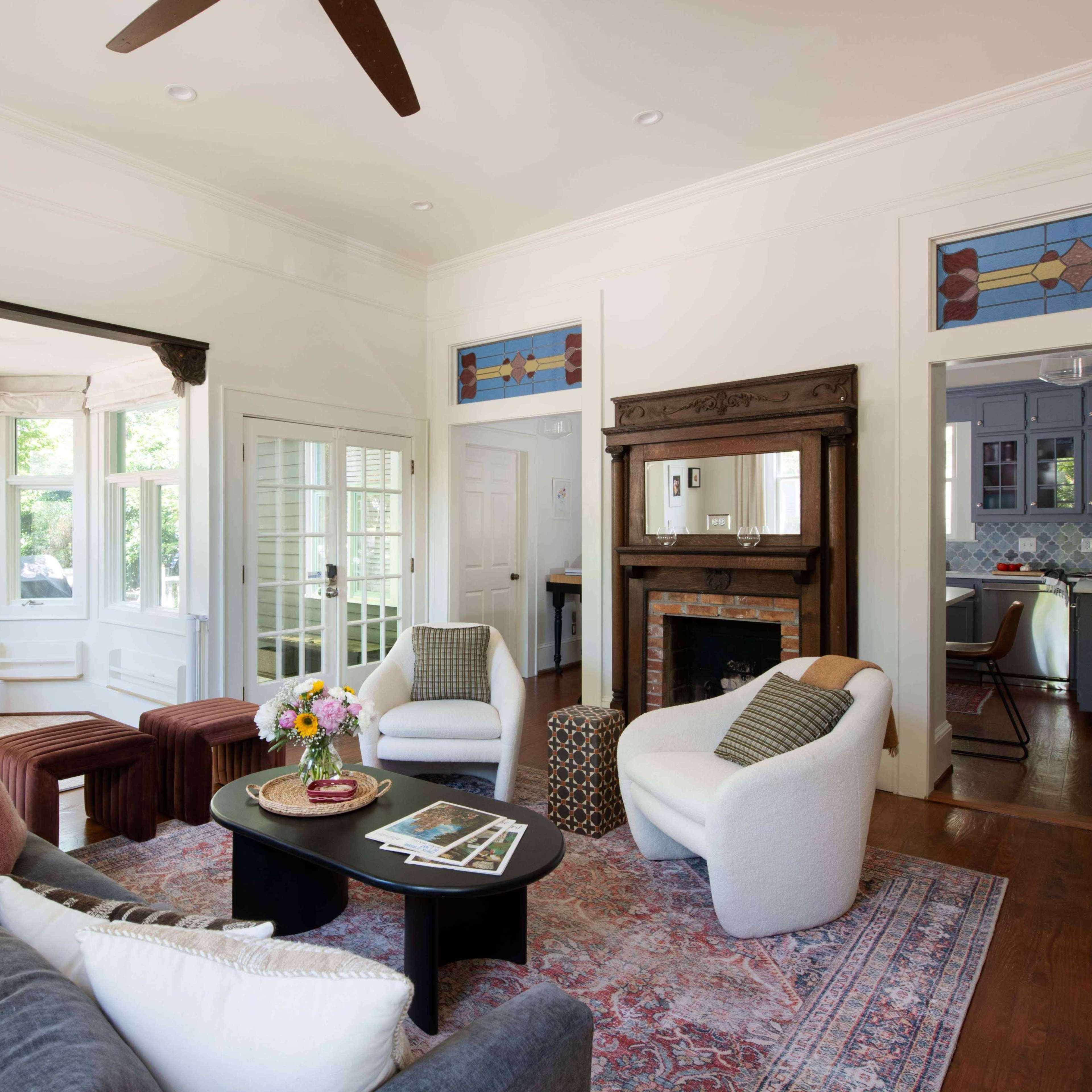 A bright living room with a seating area, a fireplace, and large windows that provide natural light.