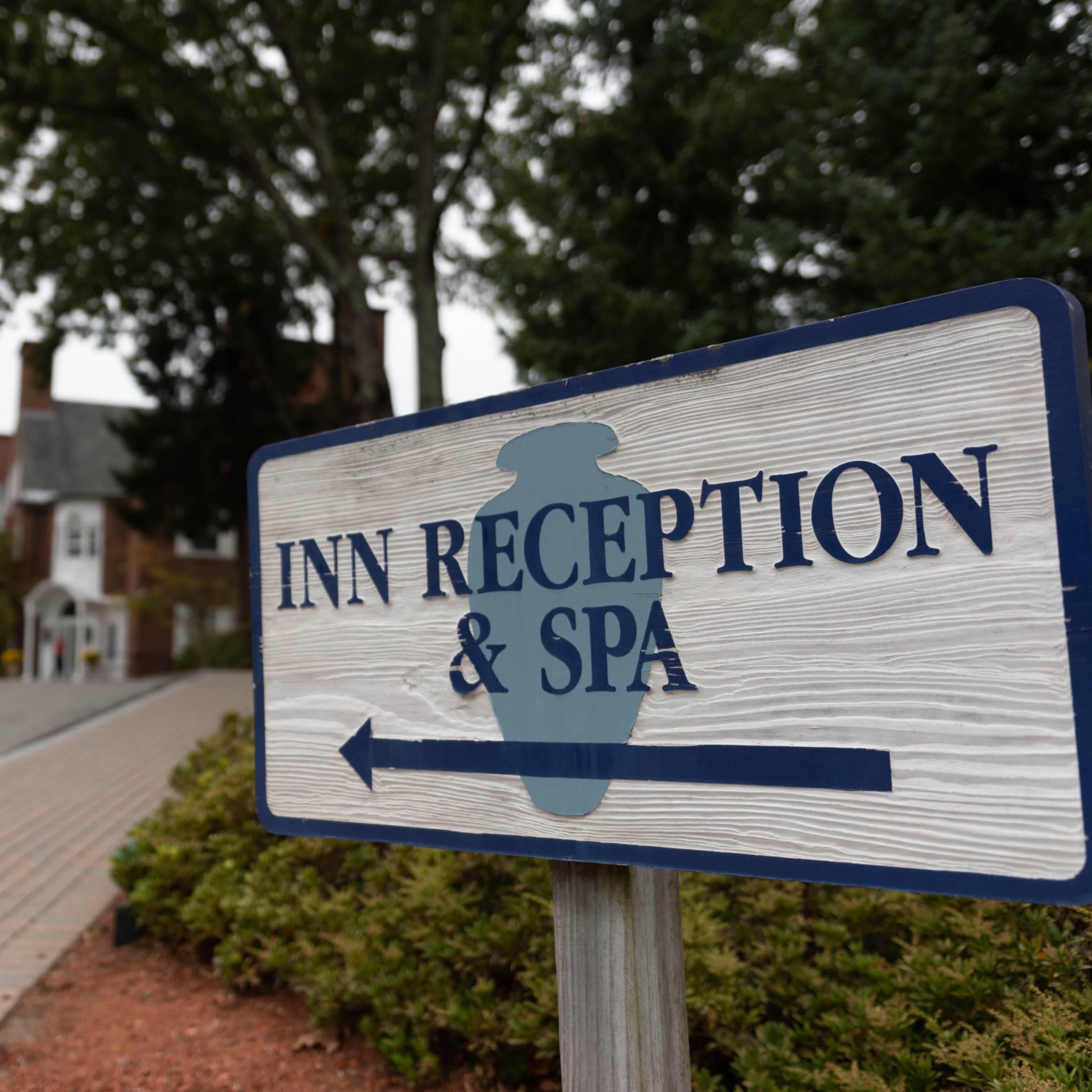 A sign indicates the direction to the inn's reception and spa, with a brick pathway and vehicles parked nearby.